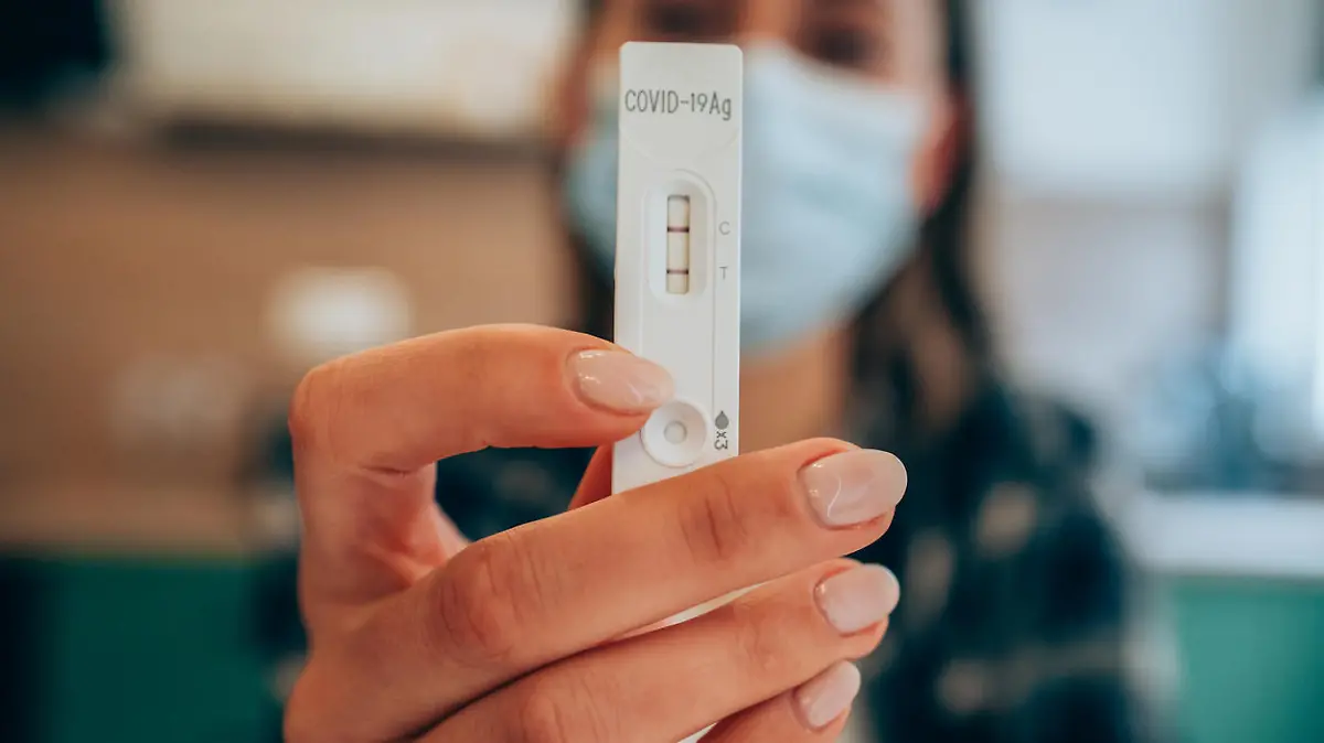 Close-up shot of doctor's hand with protective gloves holding a positive test device to senior patient. Doctor documented the result after a positive test. Doctor hand holding positive Coronavirus/Covid-19 rapid test. Focus is on the test.