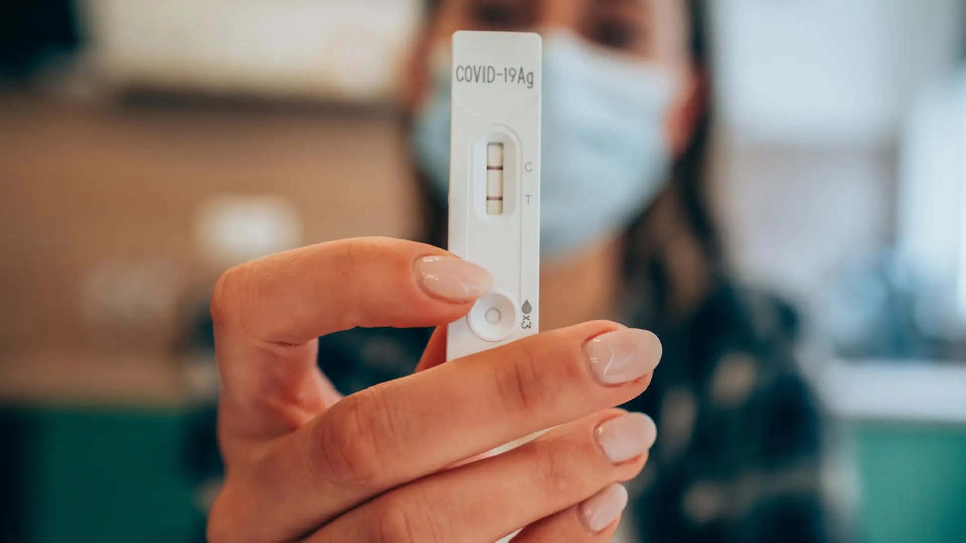 Close-up shot of doctor's hand with protective gloves holding a positive test device to senior patient. Doctor documented the result after a positive test. Doctor hand holding positive Coronavirus/Covid-19 rapid test. Focus is on the test.