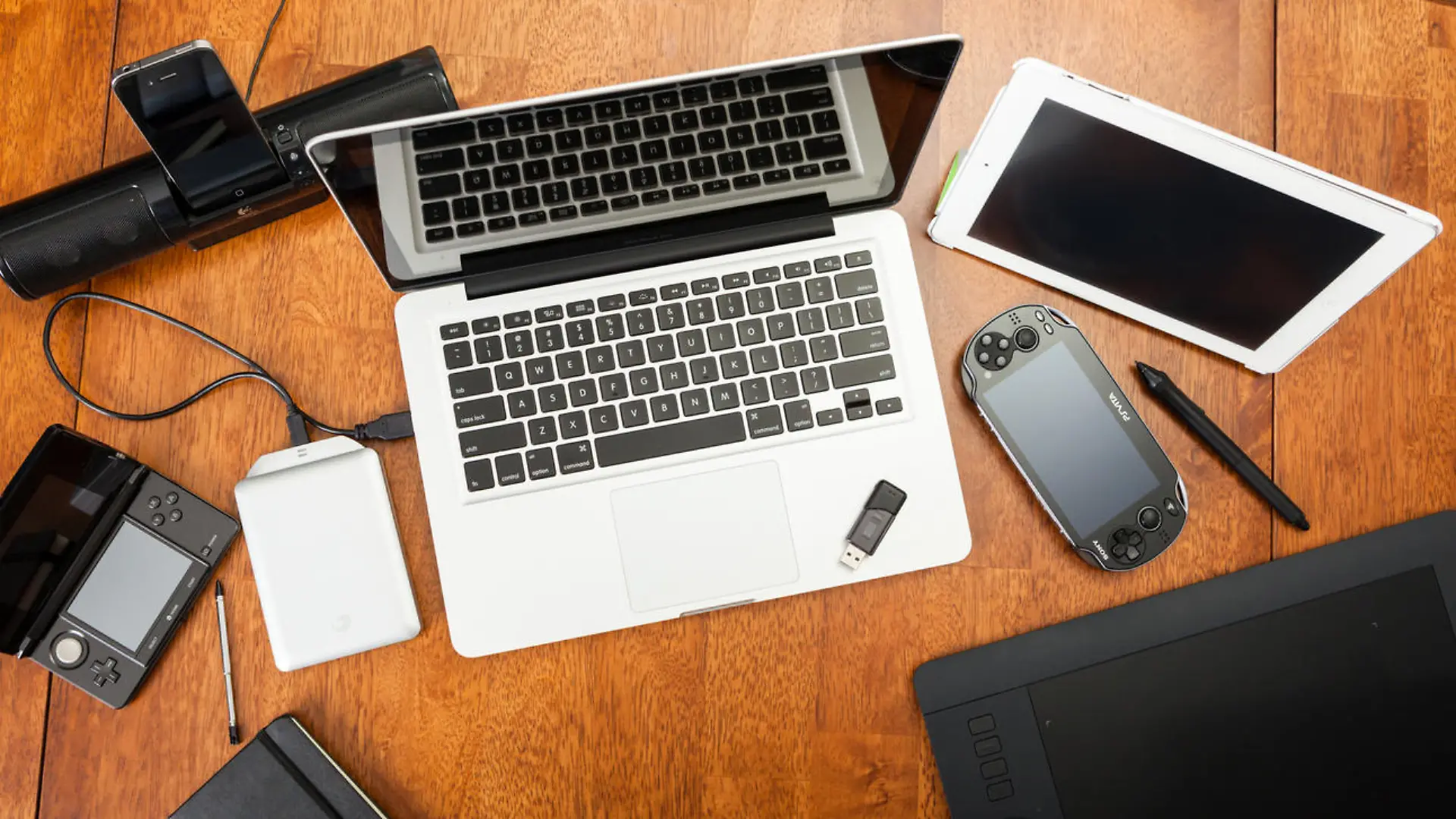 Chatham, Canada - May 22, 2014: Overhead view of a students desk. On top of the desk is an assortment of popular electronics devices. These include Apple products, laptop and iPad. There is a Playstation portable hand-held game. Also included is a Wacom drawing tablet and a hard drive. Back to school concept. There are no people in the image.