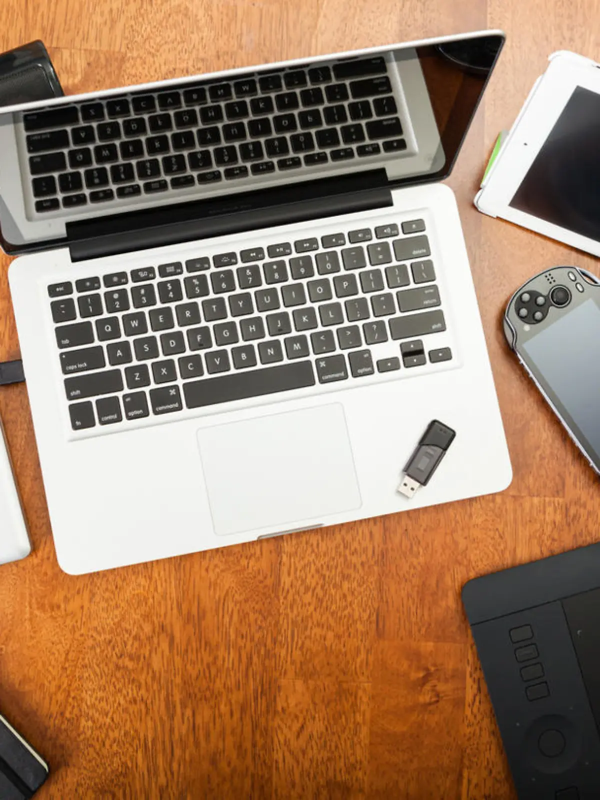 Chatham, Canada - May 22, 2014: Overhead view of a students desk. On top of the desk is an assortment of popular electronics devices. These include Apple products,  laptop and iPad. There is a Playstation portable hand-held game. Also included is a Wacom drawing tablet and a hard drive. Back to school concept. There are no people in the image. 