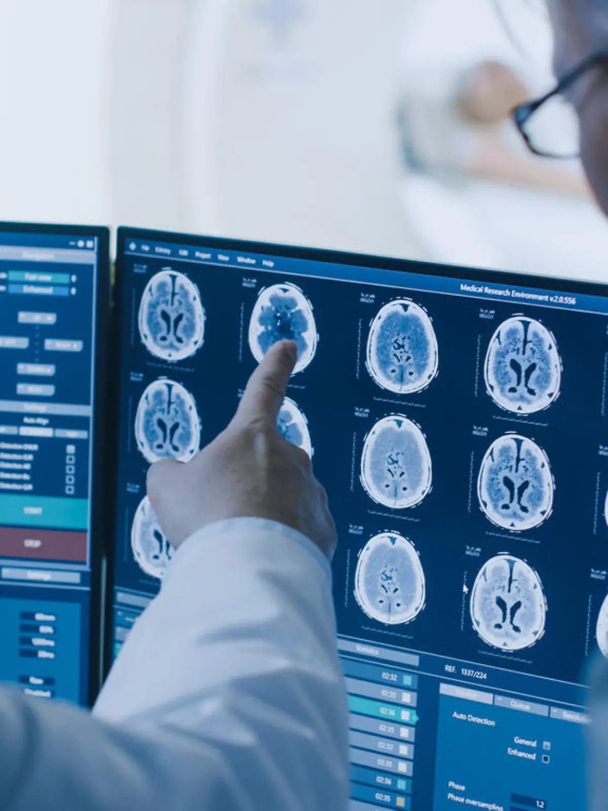 In Control Room Doctor and Radiologist Discuss Diagnosis while Watching Procedure and Monitors Showing Brain Scans Results, In the Background Patient Undergoes MRI or CT Scan Procedure.