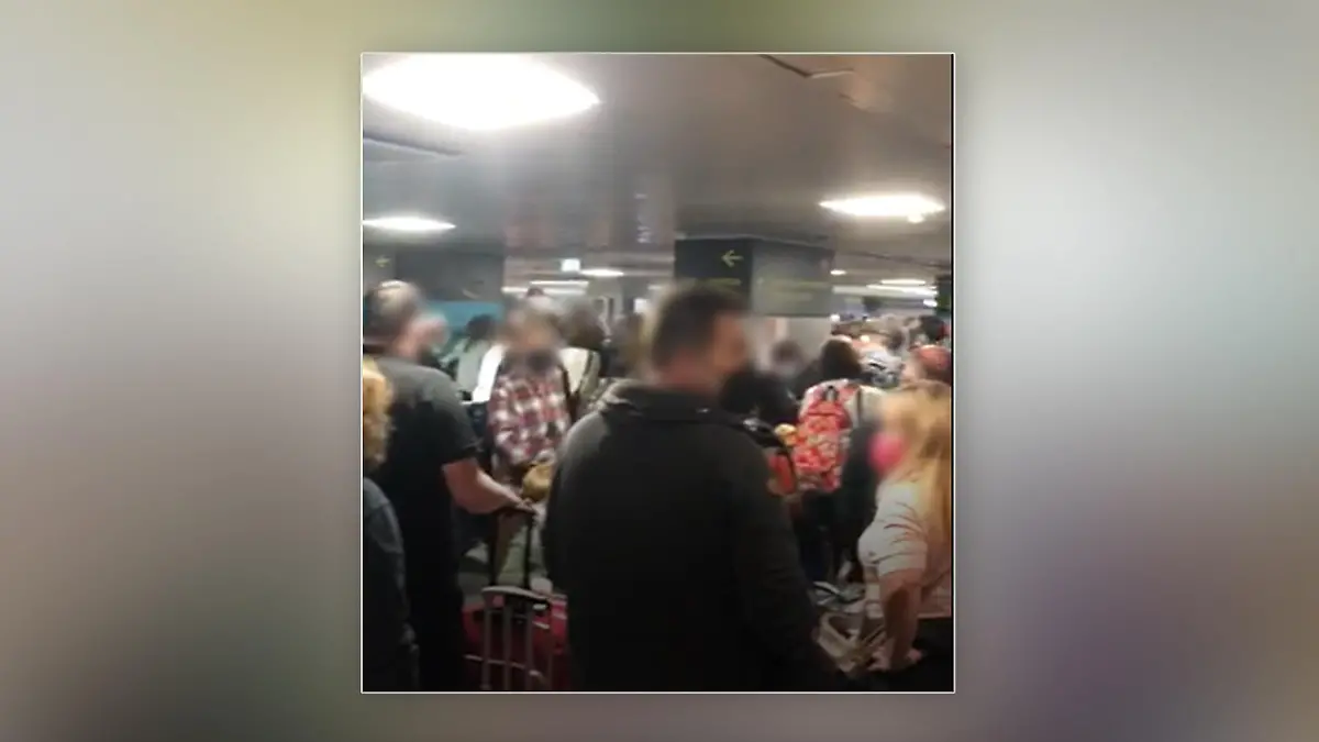 Viele Menschen stehen dicht gedrängt im Terminal eines Flughafens