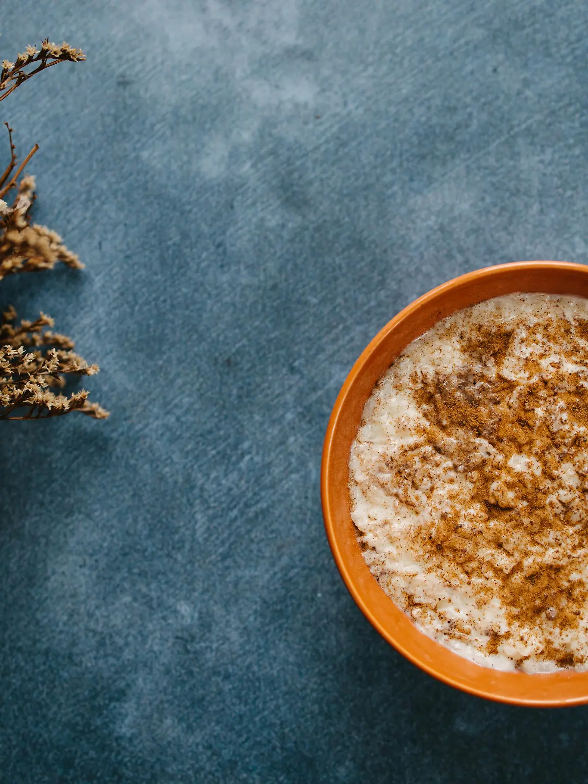Rice pudding with cinnamon and almonds on blue background