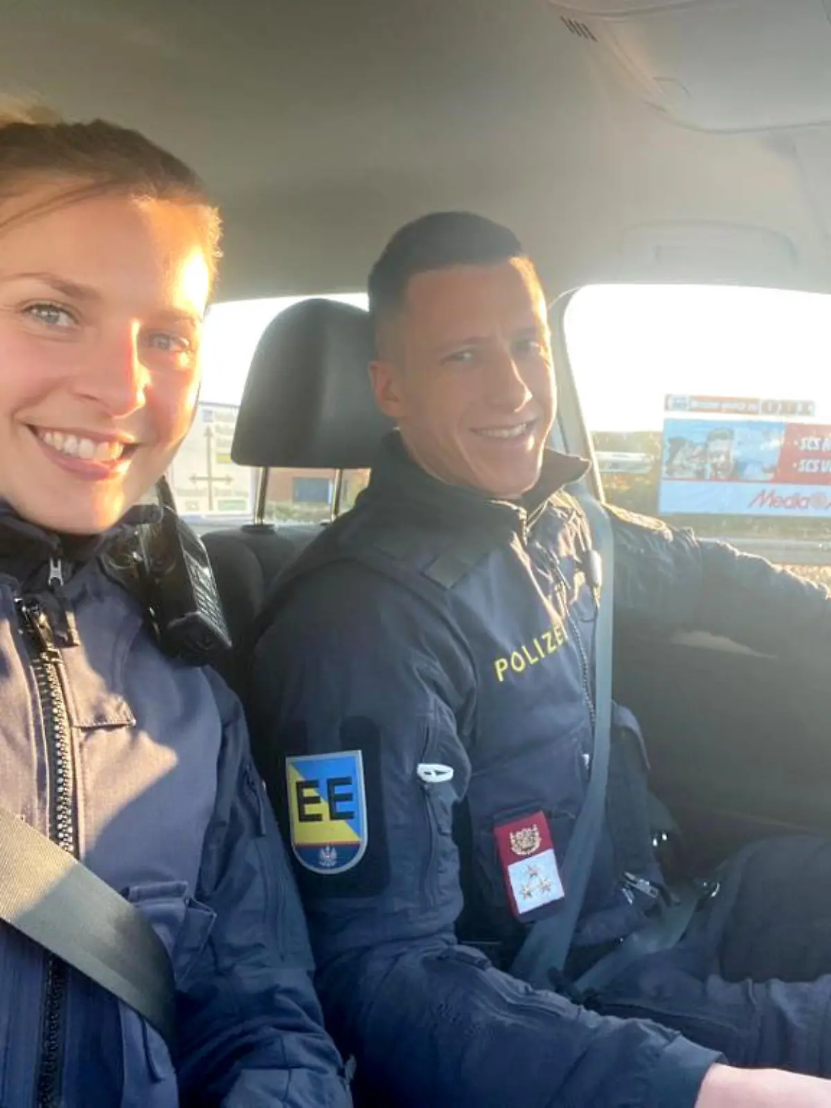 HANDOUT - 02.01.2022, Österreich, Wien: Auf diesem Handoutfoto der Polizei Niederösterreich lächelt ein Polizisten-Pärchen in einem Auto. Ein österreichisches Polizisten-Paar hat auf seinem Urlaubsflug von Frankfurt nach Vancouver einen Passagier überwältigt, der zwei Stunden nach dem Start Drohungen ausgestoßen und so die Sicherheit an Bord gefährdet hatte. Die österreichischen Streifenbeamten bewachten den Passagier stundenlang bis zur Landung in Kanada, wo er den Behörden übergeben wurde. Foto: Unbekannt/LPD NÖ/dpa - ACHTUNG: Nur zur redaktionellen Verwendung und nur mit vollständiger Nennung des vorstehenden Credits +++ dpa-Bildfunk +++