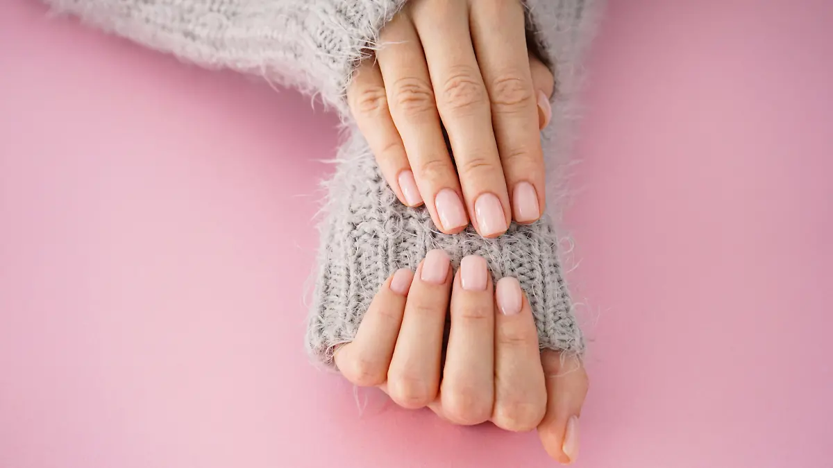 Beautiful hands of a young girl with beautiful manicure on a pink background, flat lay. Winter care, skin, Spa concept.