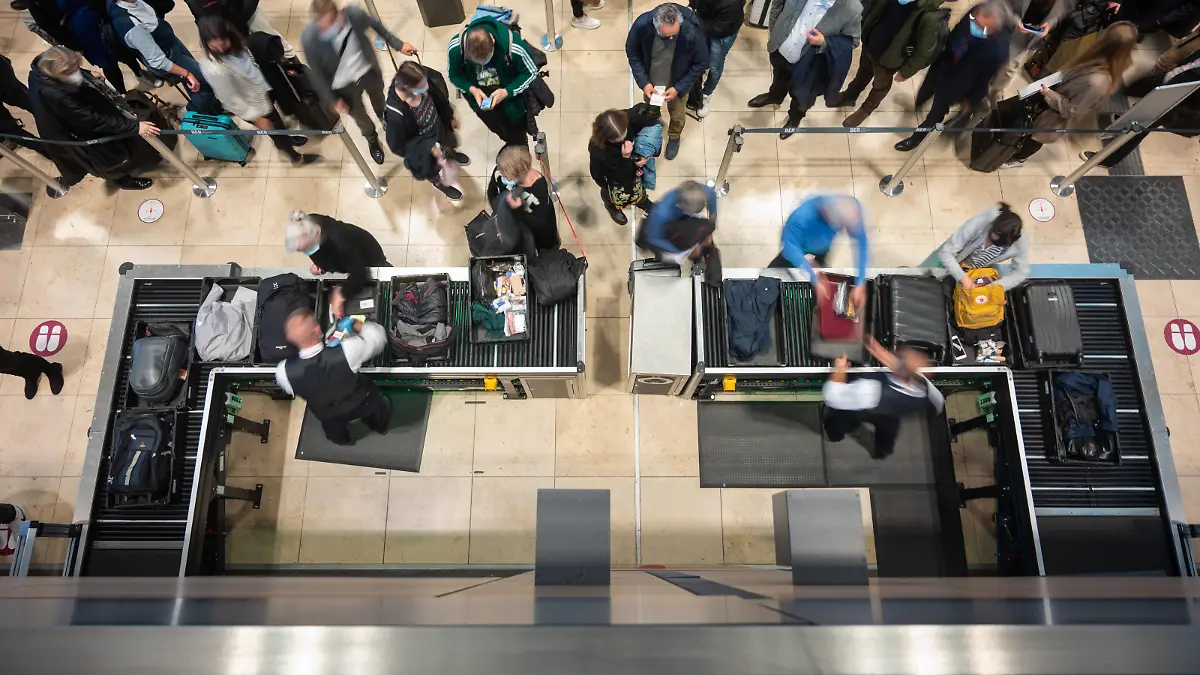 Passagiere stehen an einer Sicherheitskontrolle in Schlangen. Nach einem Feueralarm am Flughafen BER wurde der Sicherheitsbereich geräumt und die Fluggäste mussten ein zweites mal durch die Sicherheitskontrolle.