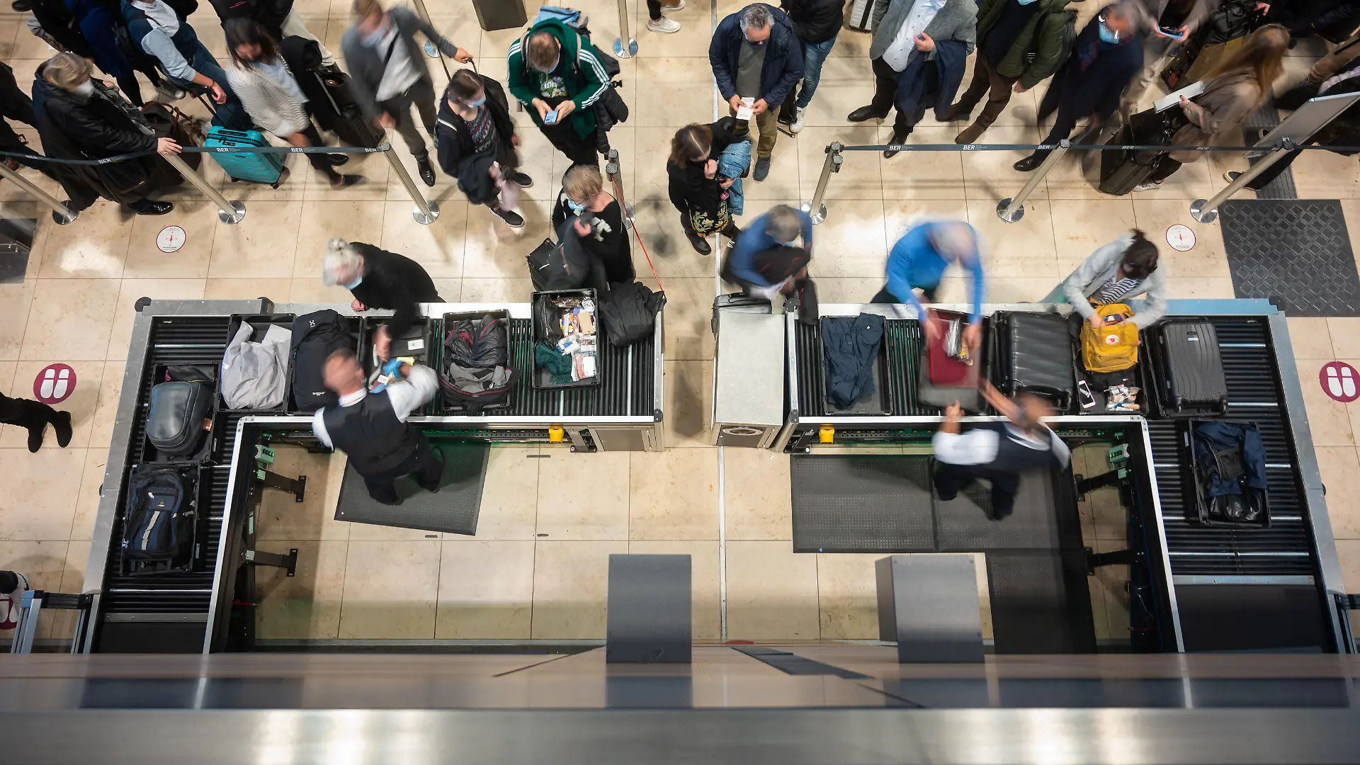 Passagiere stehen an einer Sicherheitskontrolle in Schlangen. Nach einem Feueralarm am Flughafen BER wurde der Sicherheitsbereich geräumt und die Fluggäste mussten ein zweites mal durch die Sicherheitskontrolle.