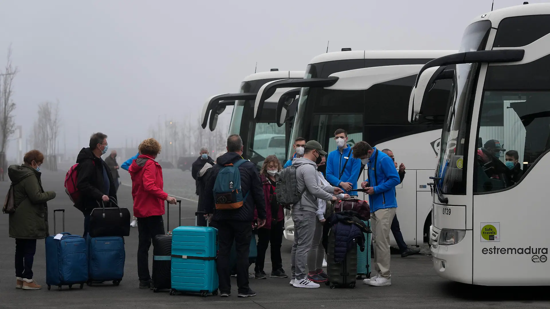 03.01.2022, Portugal, Lissabon: Passagiere stehen mit ihrem Gepäck vor einem Bus Schlange, um zum Flughafen von Lissabon gebracht zu werden, nachdem sie das Kreuzfahrtschiff Aida Nova verlassen haben. Nachdem mehrere Passagiere und Besatzungsmitglieder positiv auf das Coronavirus getestet worden sind, wurde die Kreuzfahrt vorzeitig in der portugiesischen Hauptstadt abgebrochen. Foto: Armando Franca/AP/dpa +++ dpa-Bildfunk +++