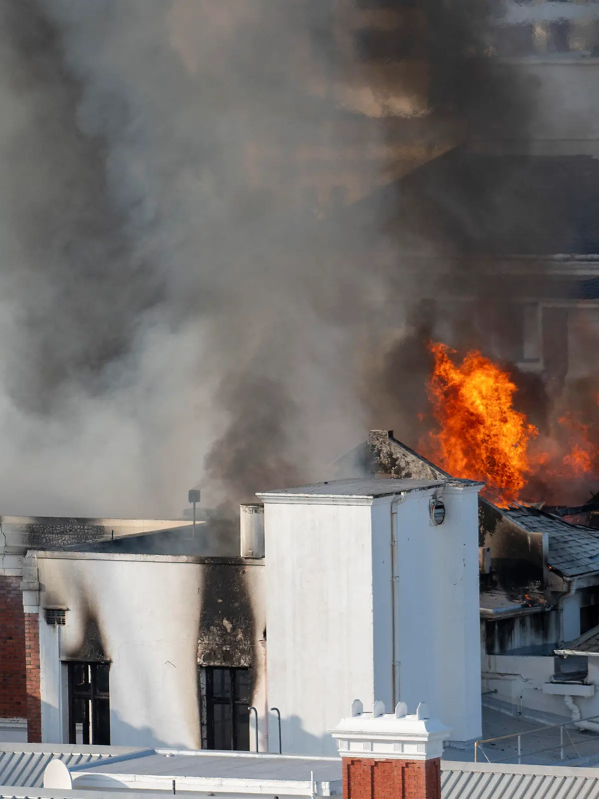 02.01.2022, Südafrika, Kapstadt: Flammen schlagen aus einem Gebäude des südafrikanischen Parlaments. Feuerwehrleute kämpften seit den frühen Morgenstunden gegen lodernde Flammen an der Rückseite des Gebäudekomplexes, der die Alte Versammlungskammer und den Nationalrat der Provinzen beherbergt. Foto: Jerome Delay/AP/dpa +++ dpa-Bildfunk +++