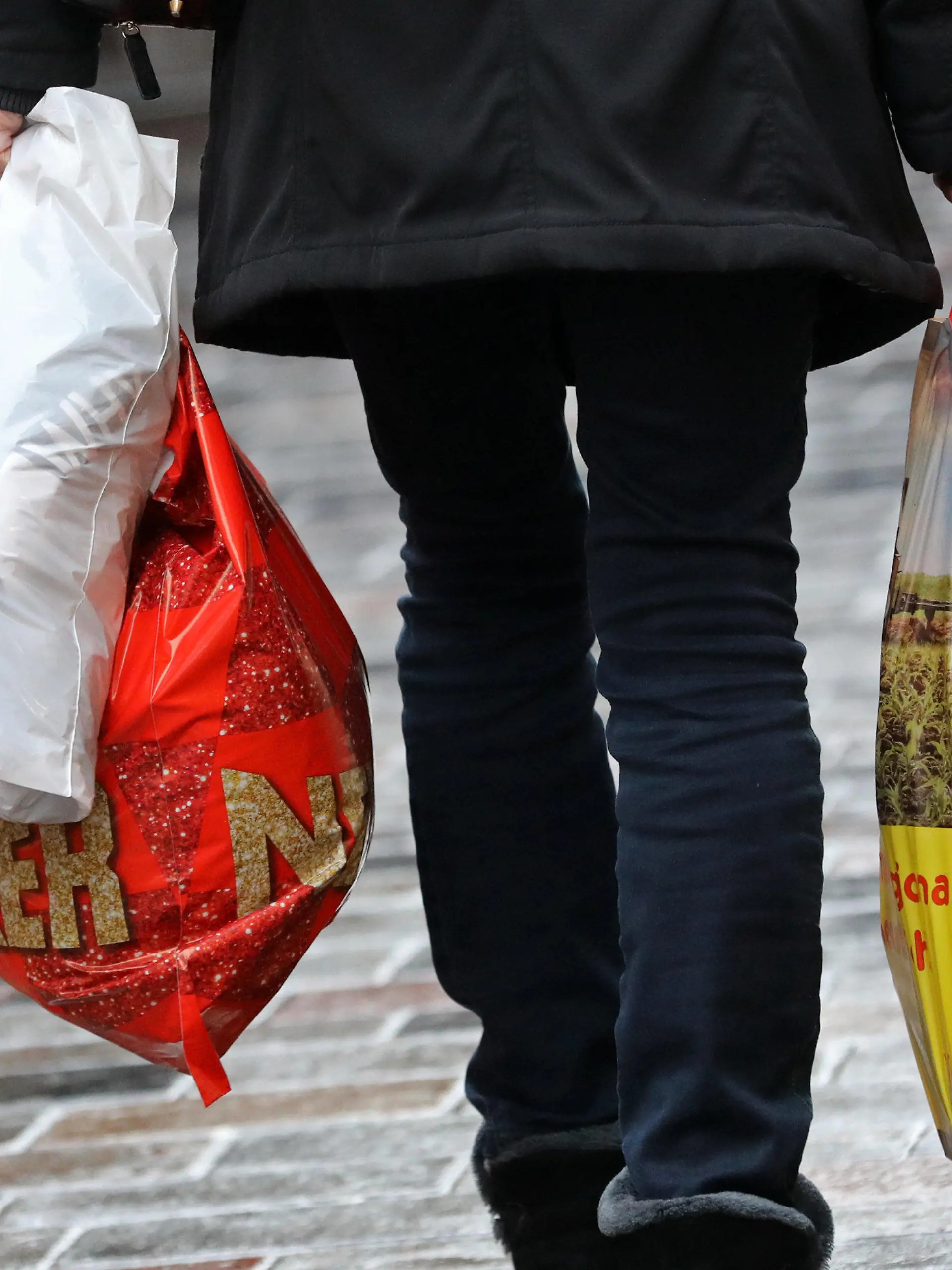 ARCHIV - 20.12.2018, Mecklenburg-Vorpommern, Rostock: Eine Frau geht mit Einkaufstüten aus Plastik über den Fußweg. Leichte Plastiktüten dürfen in Deutschland ab 2022 nicht mehr ausgegeben werden. Ab dem 1. Januar dürfen an den deutschen Ladenkassen keine Einkaufstüten aus Plastik mehr angeboten werden. Es geht um die Standard-Tüten. Foto: Bernd Wüstneck/dpa +++ dpa-Bildfunk +++