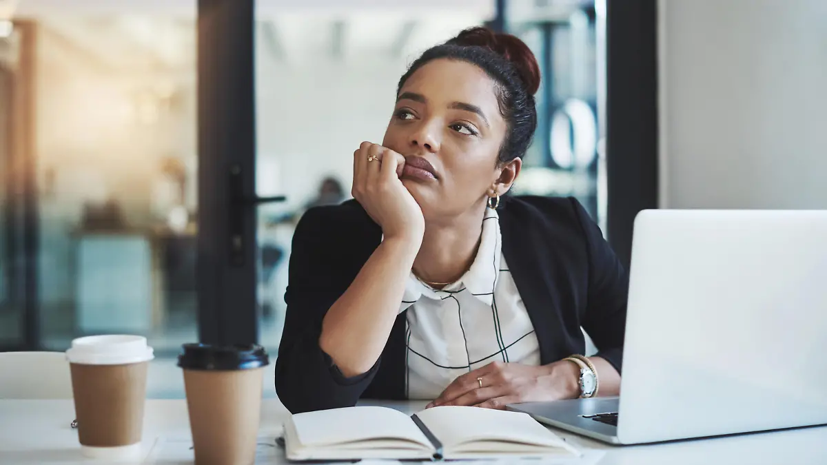 Shot of a young businesswoman looking bored while working at her desk in a modern office