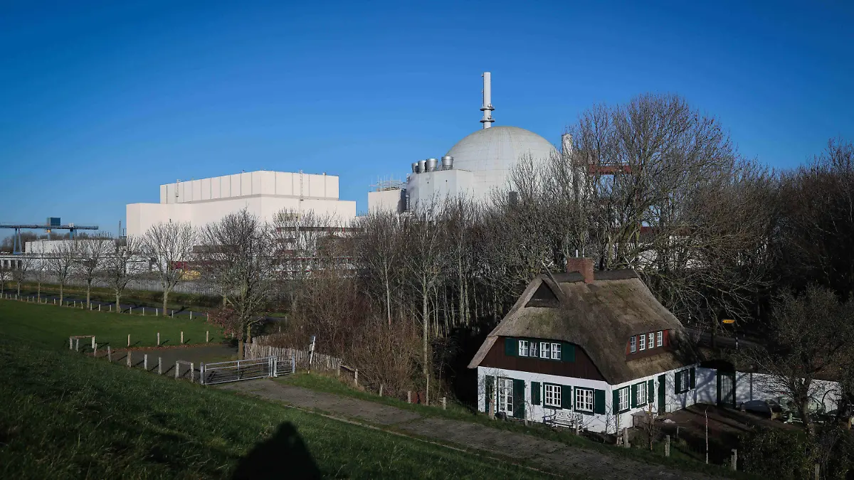 ARCHIV - 20.12.2021, Schleswig-Holstein, Brokdorf: Die Kuppel des Reaktorgebäudes des Kernkraftwerk Brokdorf ist hinter einem Reetdachhaus am Elbdeich zu sehen. (zu dpa «Energiemarktexperte: Märkte sind auf Atom-Abschaltung vorbereitet») Foto: Christian Charisius/dpa +++ dpa-Bildfunk +++
