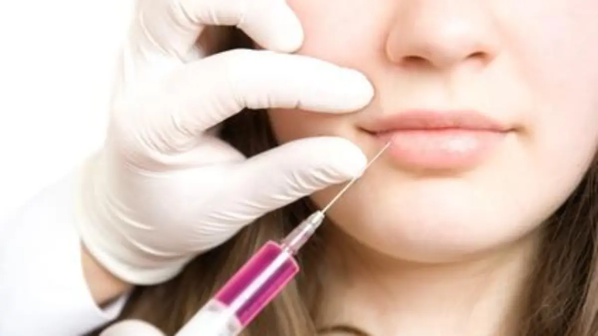 Doctor making injection in lips of young woman
