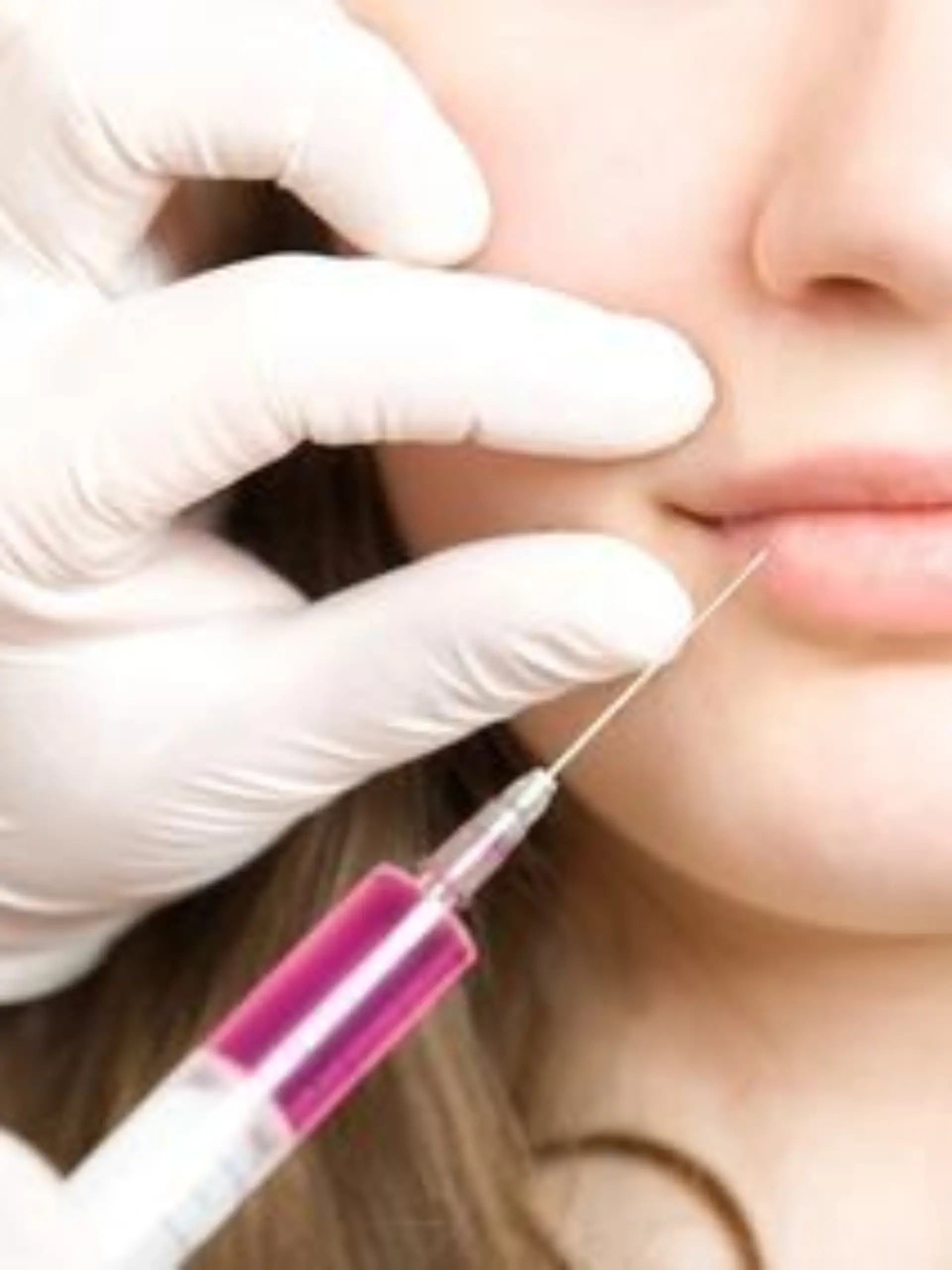 Doctor making injection in lips of young woman 