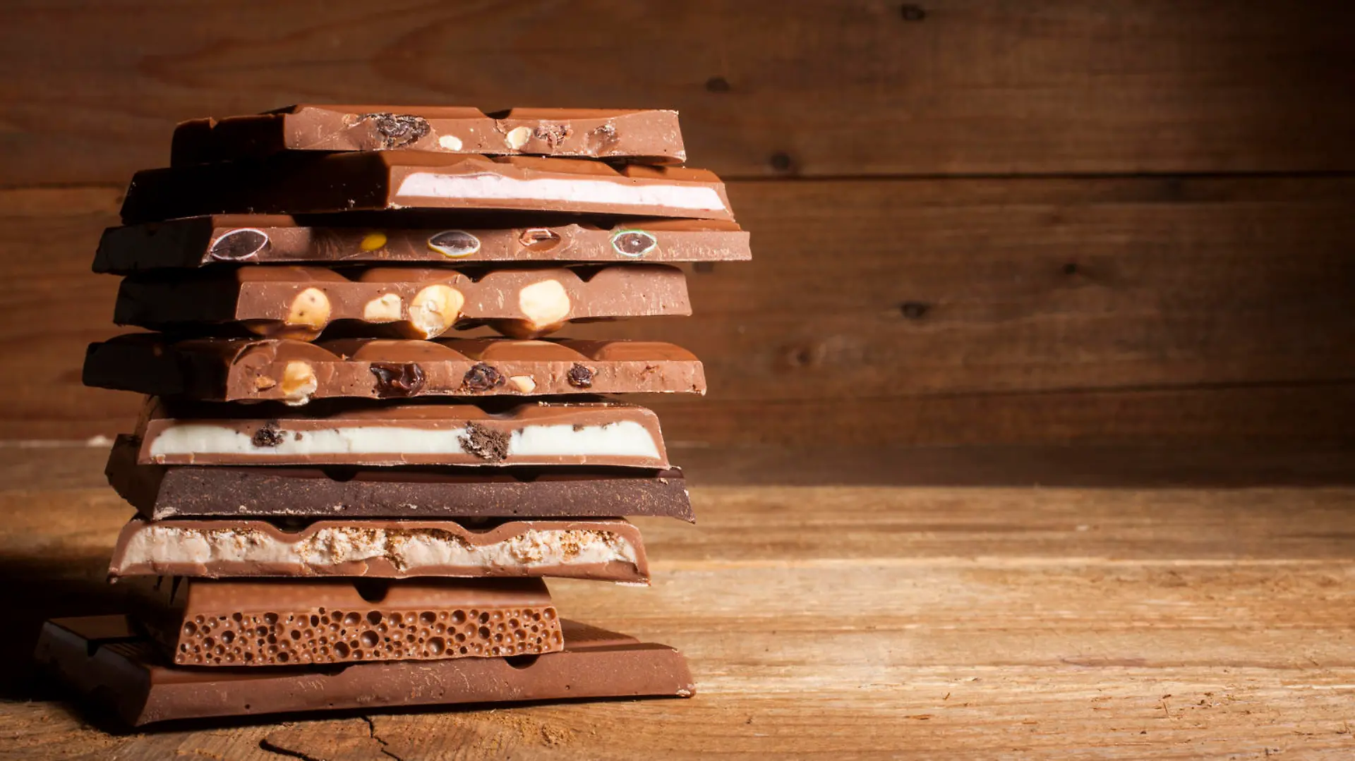 Chocolate blocks stack with different kind of chocolate on wooden background 
