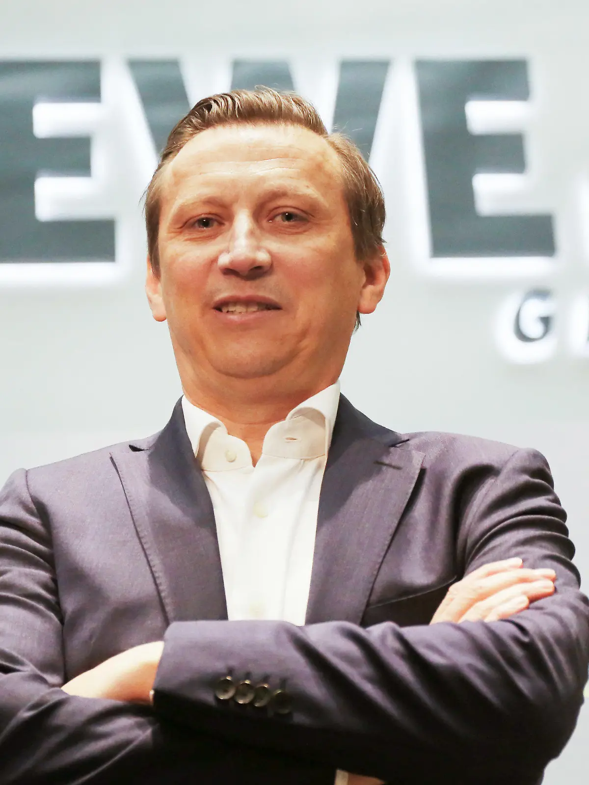 ARCHIV - 03.04.2019, Nordrhein-Westfalen, Köln: Lionel Souque, Vorstandsvorsitzender des Rewe Konzerns, steht vor dem Rewe Logo. Steigende Preise und wachsende Lieferprobeleme in der Lebensmittelbranche: Rewe macht die Industrie dafür verantwortlich. Konzernchef Souque übt deutliche Kritik. (zu dpa "Rewe-Chef: «Noch nie so viele Forderungen nach Preiserhöhungen») Foto: Oliver Berg/dpa +++ dpa-Bildfunk +++