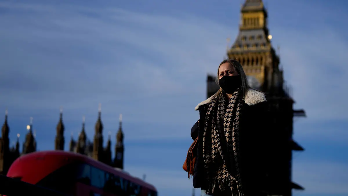 09.12.2021, Großbritannien, London: Eine Frau mit Mund-Nasen-Schutz überquert die Westminster Bridge. Premierminister Johnson kündigte als Reaktion auf steigenden Neuinfektionen und die Omikron-Variante des Coronavirus neue Corona-Beschränkungen an. Foto: Frank Augstein/AP/dpa +++ dpa-Bildfunk +++