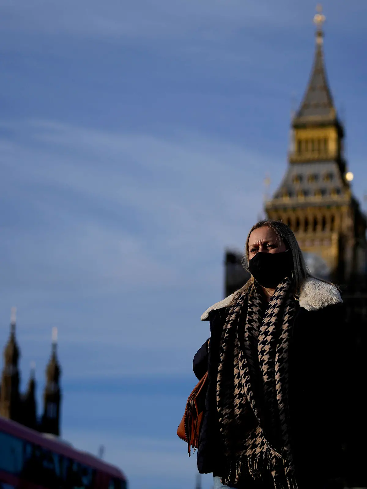 09.12.2021, Großbritannien, London: Eine Frau mit Mund-Nasen-Schutz überquert die Westminster Bridge. Premierminister Johnson kündigte als Reaktion auf steigenden Neuinfektionen und die Omikron-Variante des Coronavirus neue Corona-Beschränkungen an. Foto: Frank Augstein/AP/dpa +++ dpa-Bildfunk +++