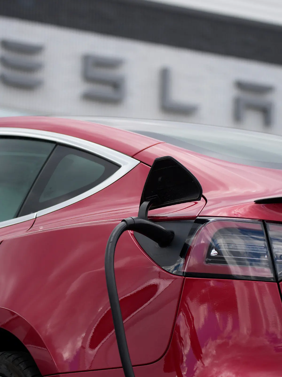 FILE - A 2021 Model 3 sedan charges at a Tesla dealership in Littleton, Colo., on June 27, 2021. Electric vehicle sales nearly doubled in the U.S. and worldwide in 2021. (AP Photo/David Zalubowski, File)