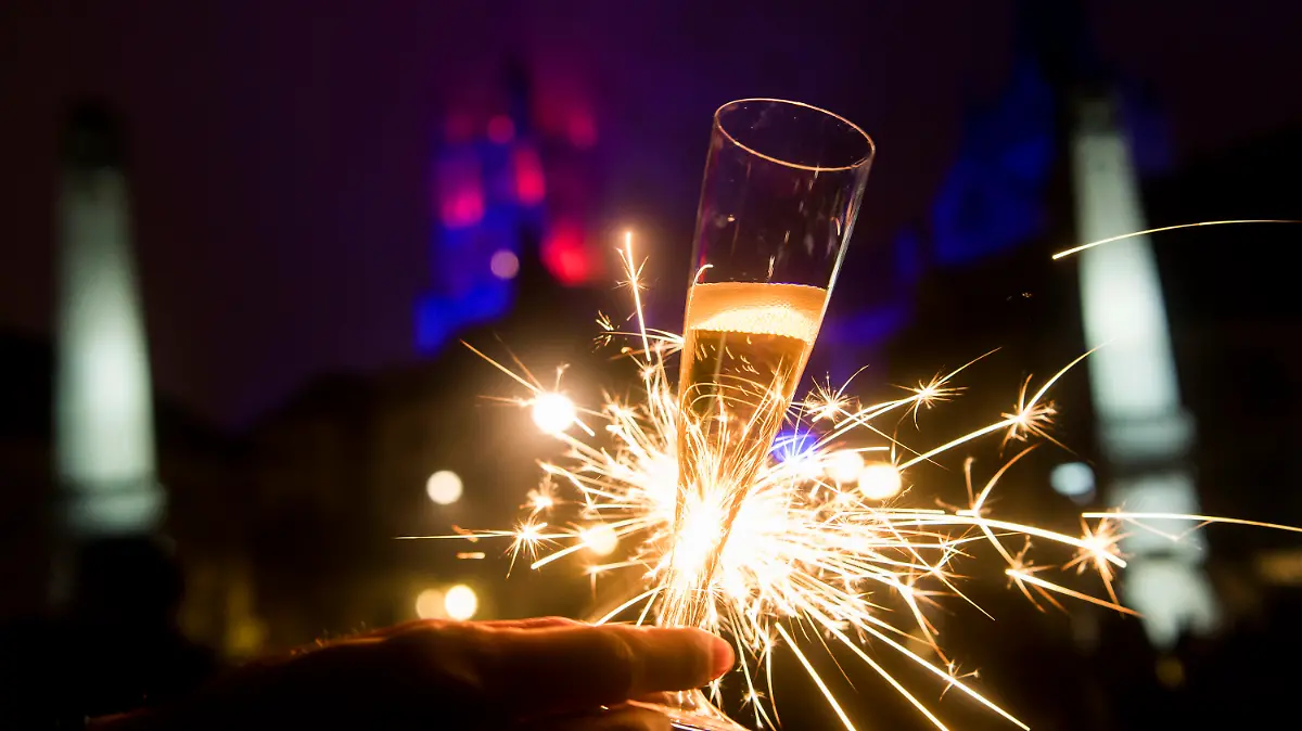 ARCHIV - 01.01.2017, Schweiz, Lausanne: Mit einem Glas Champagner und einer Wunderkerze in der Hand feiert eine Frau den Jahreswechsel. Kommt das Böllerverbot zu Silvester oder nicht? Wenn es um die Feiertage geht, scheint vielen in Deutschland Weihnachten wichtiger als der Jahreswechsel. (zu dpa "Wird Silvester geopfert? Böllerverbot stößt zumindest auf Verständnis") Foto: Jean-Christophe Bott/KEYSTONE/dpa +++ dpa-Bildfunk +++