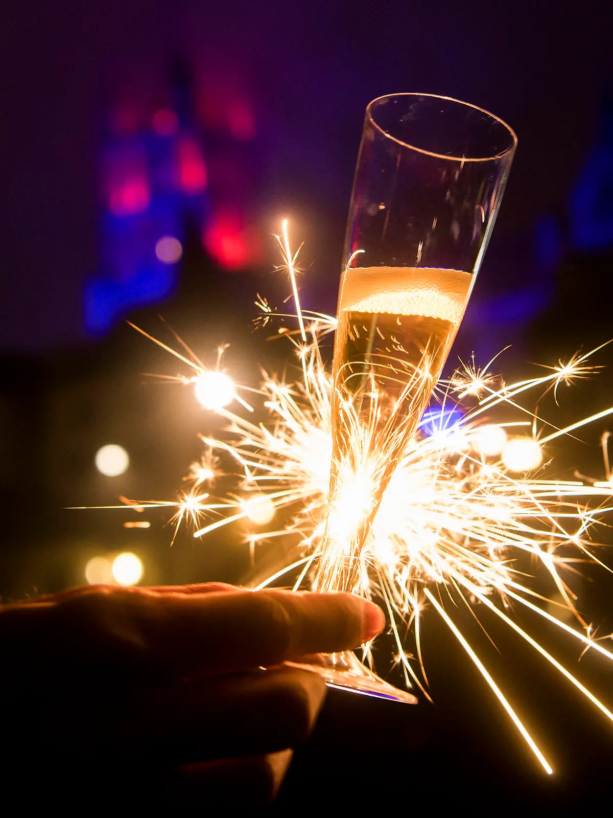 ARCHIV - 01.01.2017, Schweiz, Lausanne: Mit einem Glas Champagner und einer Wunderkerze in der Hand feiert eine Frau den Jahreswechsel. Kommt das Böllerverbot zu Silvester oder nicht? Wenn es um die Feiertage geht, scheint vielen in Deutschland Weihnachten wichtiger als der Jahreswechsel. (zu dpa "Wird Silvester geopfert? Böllerverbot stößt zumindest auf Verständnis") Foto: Jean-Christophe Bott/KEYSTONE/dpa +++ dpa-Bildfunk +++