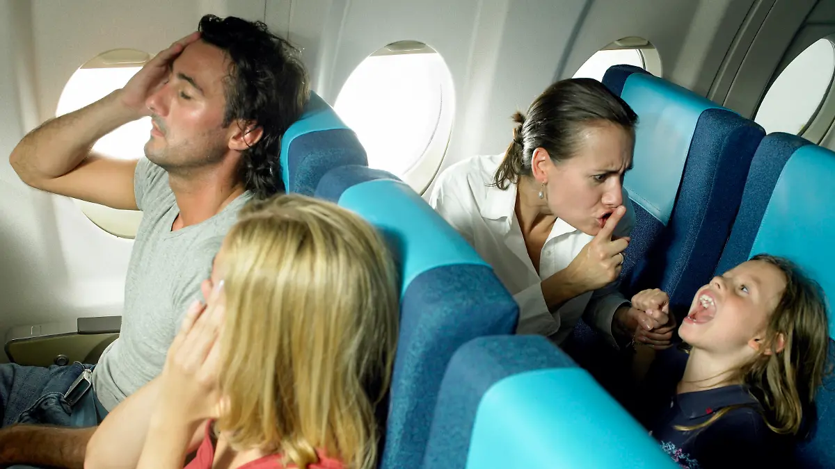 Schreiendes Mädchen, das im Flugzeug hinter einem Pärchen schreit