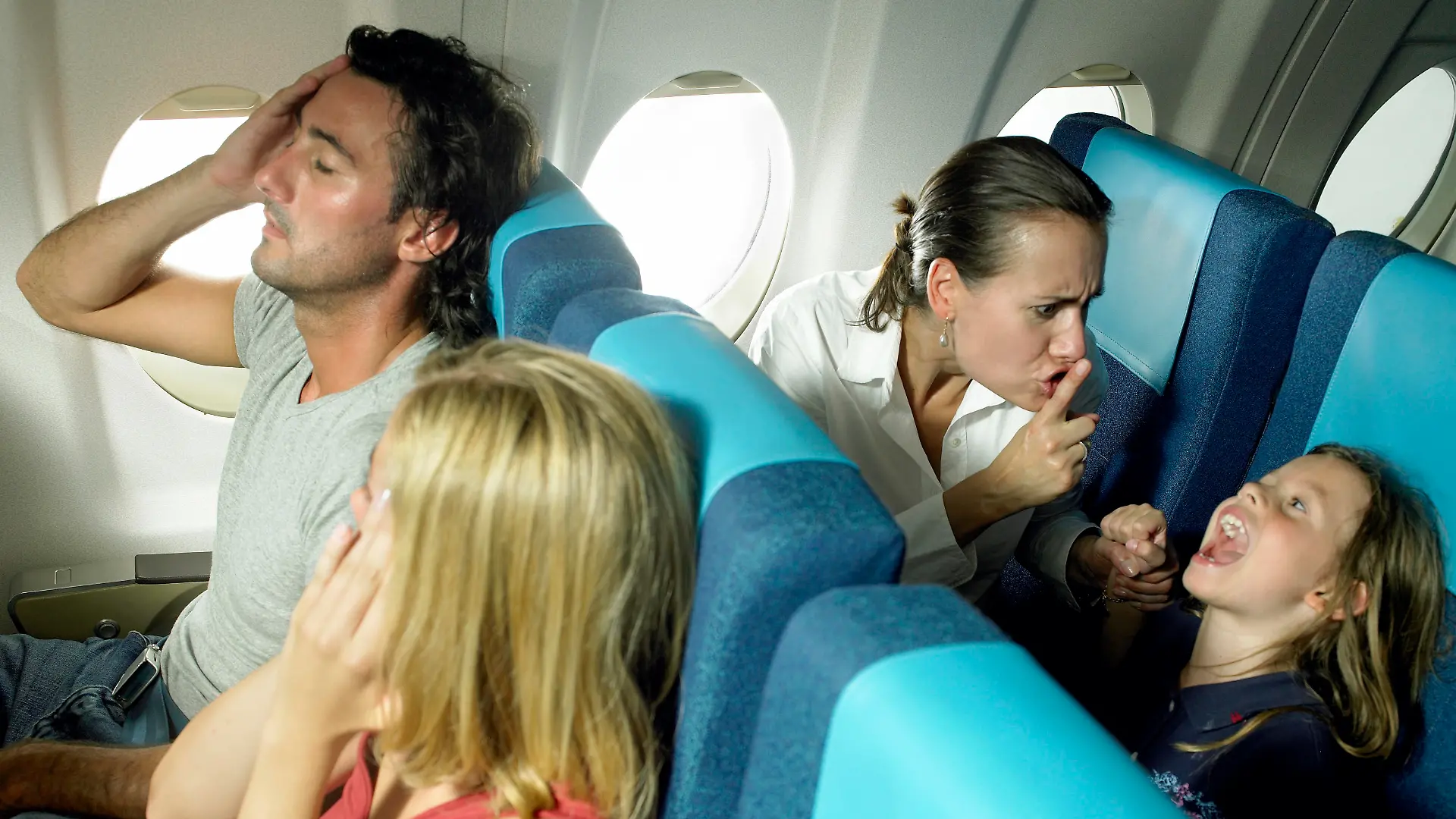 Schreiendes Mädchen, das im Flugzeug hinter einem Pärchen schreit