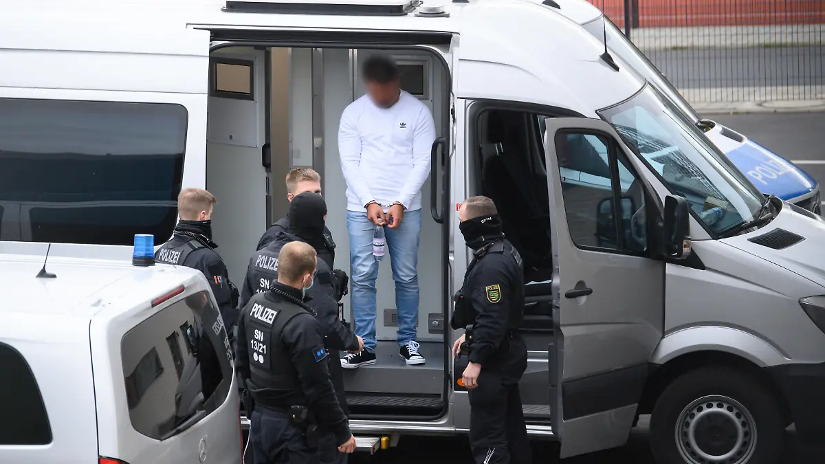 Ein verdächtiger Mann im Fall um den Kunstdiebstahl im Grünen Gewölbe wird von Polizisten in das Gebäude des Oberlandesgerichts geführt. Knapp ein Jahr nach dem Kunstraub im Dresdner Grünen Gewölbe hat die Polizei am Morgen in Berlin drei Tatverdächtige festgenommen.