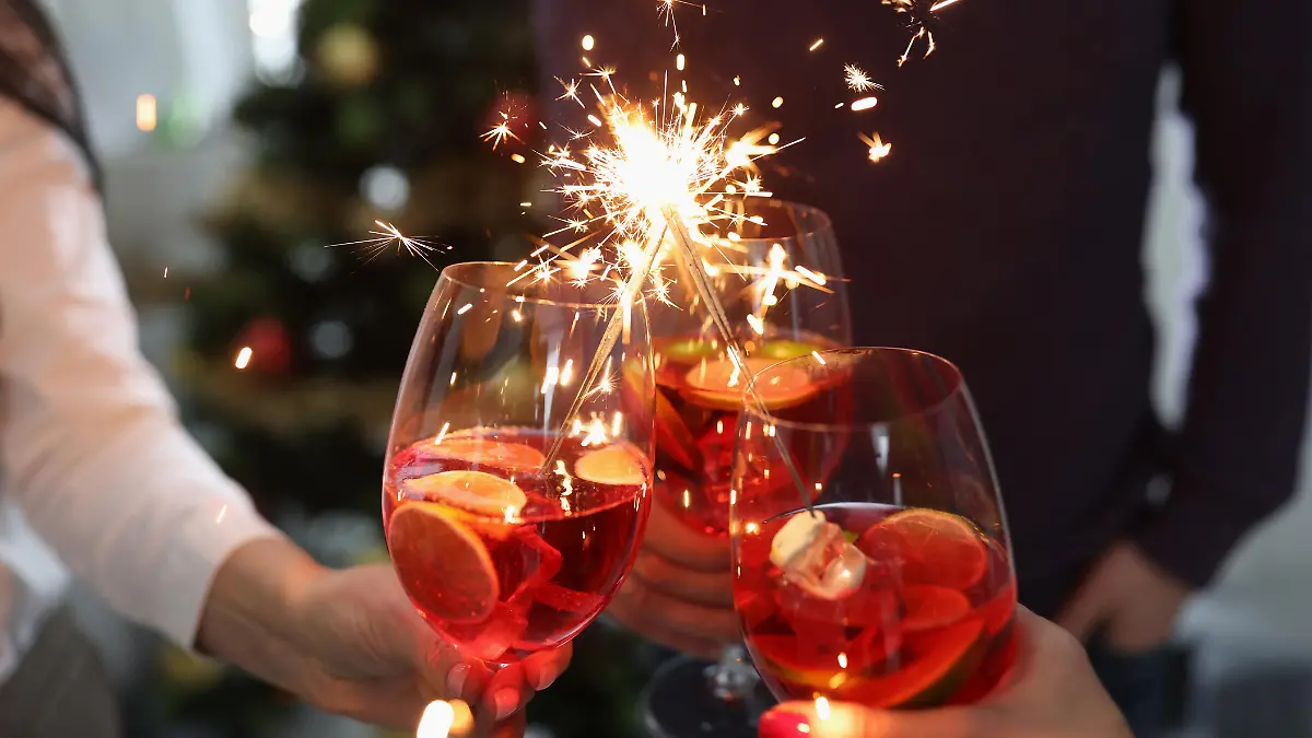 Group of people holding glasses with cocktails and sparklers closeup. New Years and Christmas celebrations concept