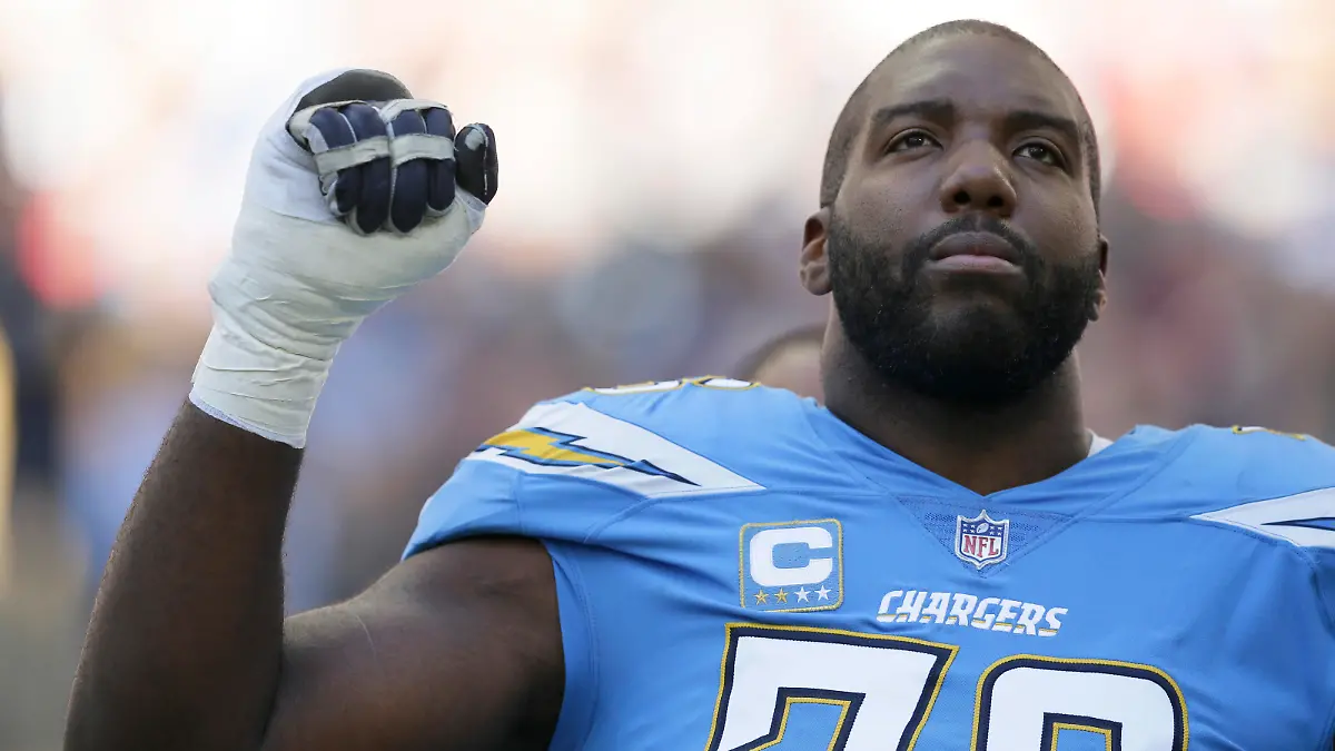Los Angeles Chargers offensive tackle Russell Okung (76), raises his fist during the national anthem before an NFL football game against Tennessee Titans at Wembley stadium in London, Sunday, Oct. 21, 2018. (AP Photo/Tim Ireland)