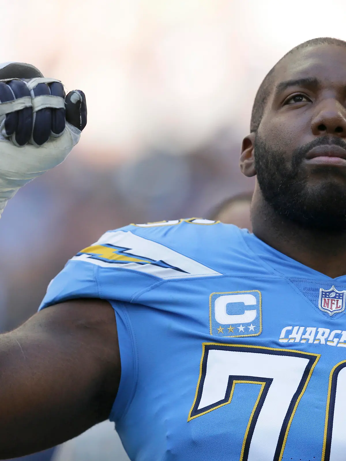 Los Angeles Chargers offensive tackle Russell Okung (76), raises his fist during the national anthem before an NFL football game against Tennessee Titans at Wembley stadium in London, Sunday, Oct. 21, 2018. (AP Photo/Tim Ireland)