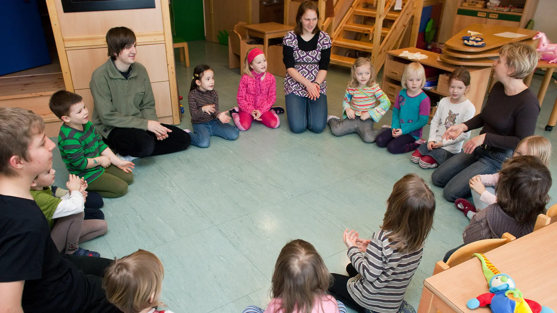 ARCHIV - Kinder, Erzieher und Praktikanten sitzen im Kindergarten "Spielhaus" im brandenburgischen Frankfurt (Oder) im Kreis auf dem Fußboden und spielen gemeinsam (Archivfoto vom 15.02.2010). Viele Eltern im Südwesten Deutschlands müssen sich ab September auf eine böse Überraschung einstellen: Angesichts wegbrechender Steuereinnahmen und steigender Kosten haben nicht wenige Städte und Gemeinden beschlossen, die Kindergartengebühren zuerhöhen. Allerdings folgen nicht alle Kommunen der Empfehlung der kommunalen Spitzenverbände und Kirchen, die Beiträge den gestiegenen Kosten anzupassen, wie eine dpa-Umfrage ergab. Foto: Patrick Pleul dpa (Zu lsw 7132) +++(c) dpa - Bildfunk+++