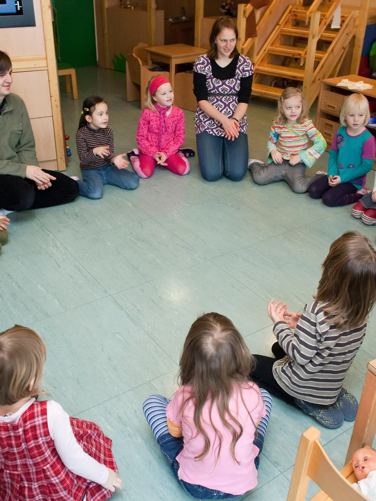 ARCHIV - Kinder, Erzieher und Praktikanten sitzen im Kindergarten "Spielhaus" im brandenburgischen Frankfurt (Oder) im Kreis auf dem Fußboden und spielen gemeinsam (Archivfoto vom 15.02.2010). Viele Eltern im Südwesten Deutschlands müssen sich ab September auf eine böse Überraschung einstellen: Angesichts wegbrechender Steuereinnahmen und steigender Kosten haben nicht wenige Städte und Gemeinden beschlossen, die Kindergartengebühren zuerhöhen. Allerdings folgen nicht alle Kommunen der Empfehlung der kommunalen Spitzenverbände und Kirchen, die Beiträge den gestiegenen Kosten anzupassen, wie eine dpa-Umfrage ergab. Foto: Patrick Pleul dpa (Zu lsw 7132)  +++(c) dpa - Bildfunk+++
