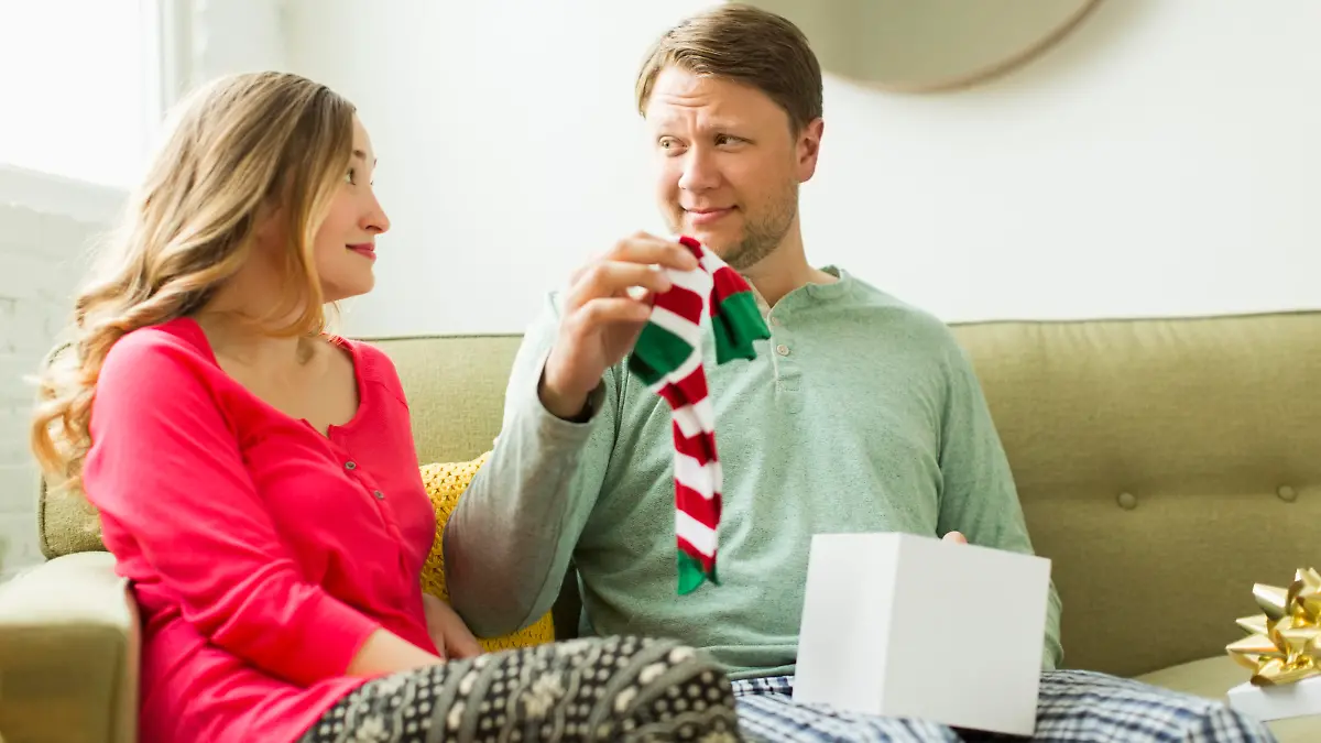 Ein Mann bekommt Socken von seiner Partnerin geschenkt.