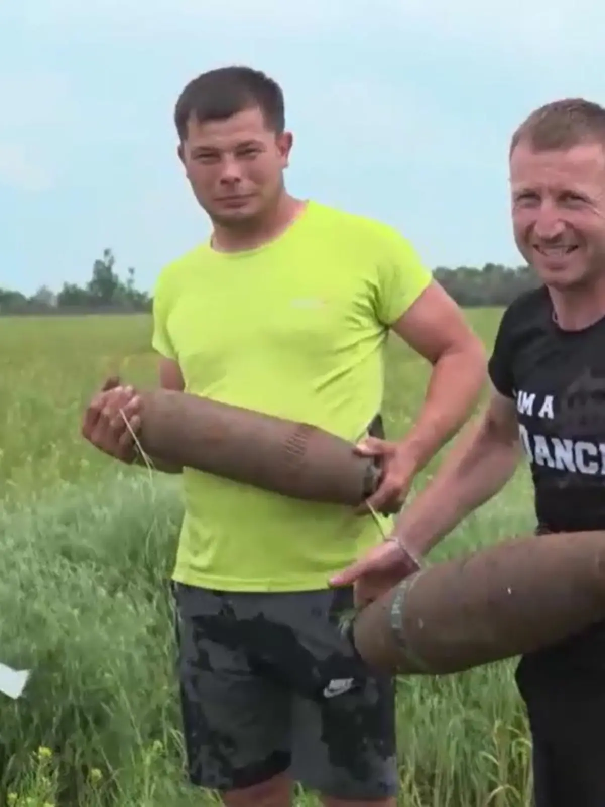 Bauer Vitali (links) und sein Kumpel Andrej (rechts) mit dem letzten Blindgänger, den sie aus einem Getreidefeld gezogen haben.