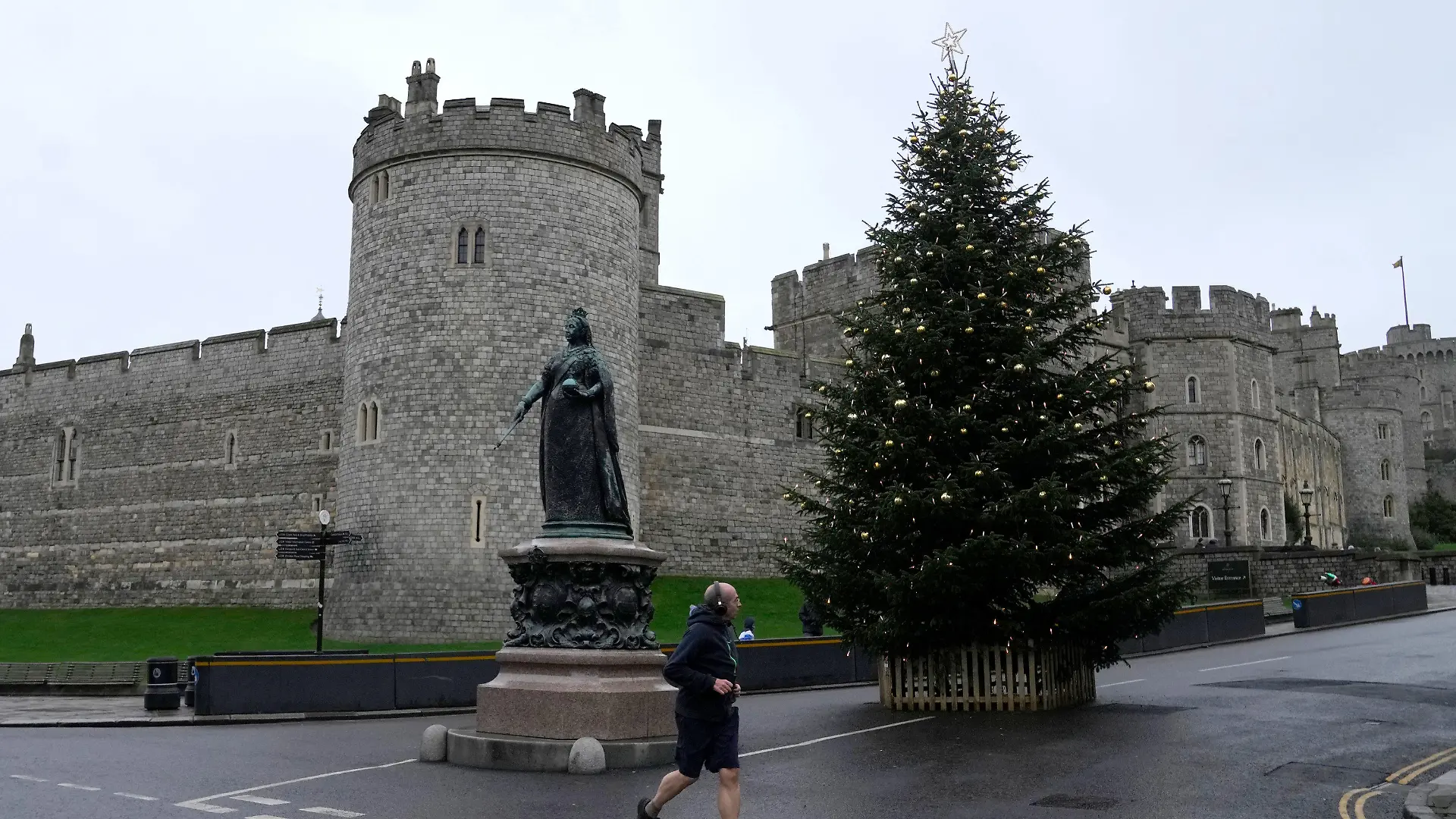 25.12.2021, Großbritannien, Windsor: Ein Jogger läuft am ersten Weihnachtstag am Schloss Windsor vorbei. Die britische Königin Elizabeth II. ist wegen der anhaltenden Corona-Pandemie auf Schloss Windsor geblieben, anstatt Weihnachten auf ihrem Landsitz Sandringham zu verbringen. Foto: Alastair Grant/AP/dpa +++ dpa-Bildfunk +++