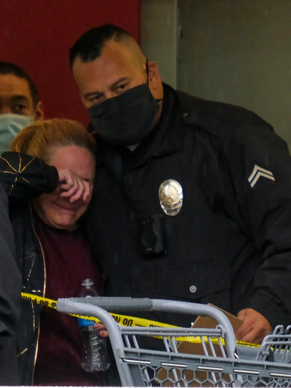 A police officer comforts a woman at the scene where two people were struck by gunfire in a shooting at a Burlington store as part of a chain formerly known as Burlington Coat Factory in North Hollywood, Calif., Thursday, Dec. 23, 2021. (AP Photo/Ringo H.W. Chiu)