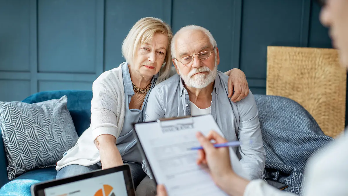 Senior couple with sad emotions during the meeting with financial consultant, signing some agreement in the office