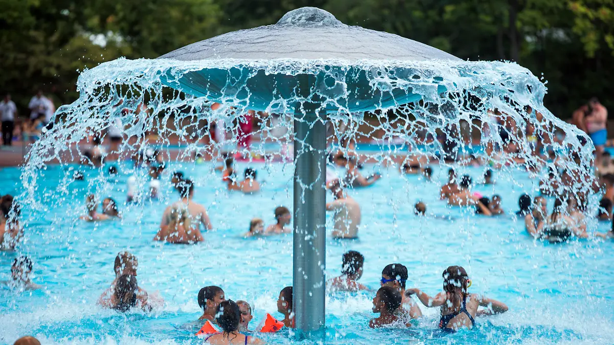 01.08.2018, Berlin: Badegäste stehen am Rande eines Pressetermins der Berliner Bäder-Betriebe im Prinzenbad im Stadtbezirk Kreuzberg unter einem Wasserpilz. Dank des hochsommerlichen Wetters und gesenkten Eintrittspreisen für Hallenbäder geht der Betrieb von deutlich höheren Besucherzahlen aus. Bis Ende Juli 2018 haben bisher über 1,3 Millionen Gäste die Bäder besucht. Foto: Jens Büttner/dpa-Zentralbild/dpa +++ dpa-Bildfunk +++