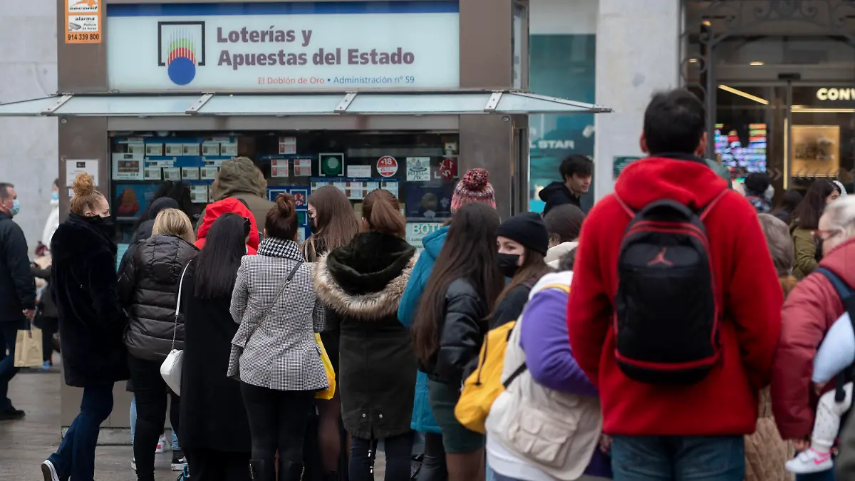 ARCHIV - 07.12.2021, Spanien, Madrid: Weniger als drei Wochen vor der außerordentlichen Weihnachtslotterie-Ziehung von Spanien stehen mehrere Personen vor einer Lotto-Annahmestelle im Zentrum von Madrid Schlange. Jedes Jahr bilden sich vor der Weihnachtsziehung am 22. Dezember lange Schlangen vor der berühmten Lotto-Annahmestelle. Die Weihnachtslotterie gilt als größte und älteste Tombola der Welt. Die Gewinnzahlen der «Lotería de Navidad» werden von Schulkindern im Madrider Opernhaus vorgesungen und die Zeremonie live im TV übertragen. Foto: Alberto Ortega/EUROPA PRESS/dpa +++ dpa-Bildfunk +++