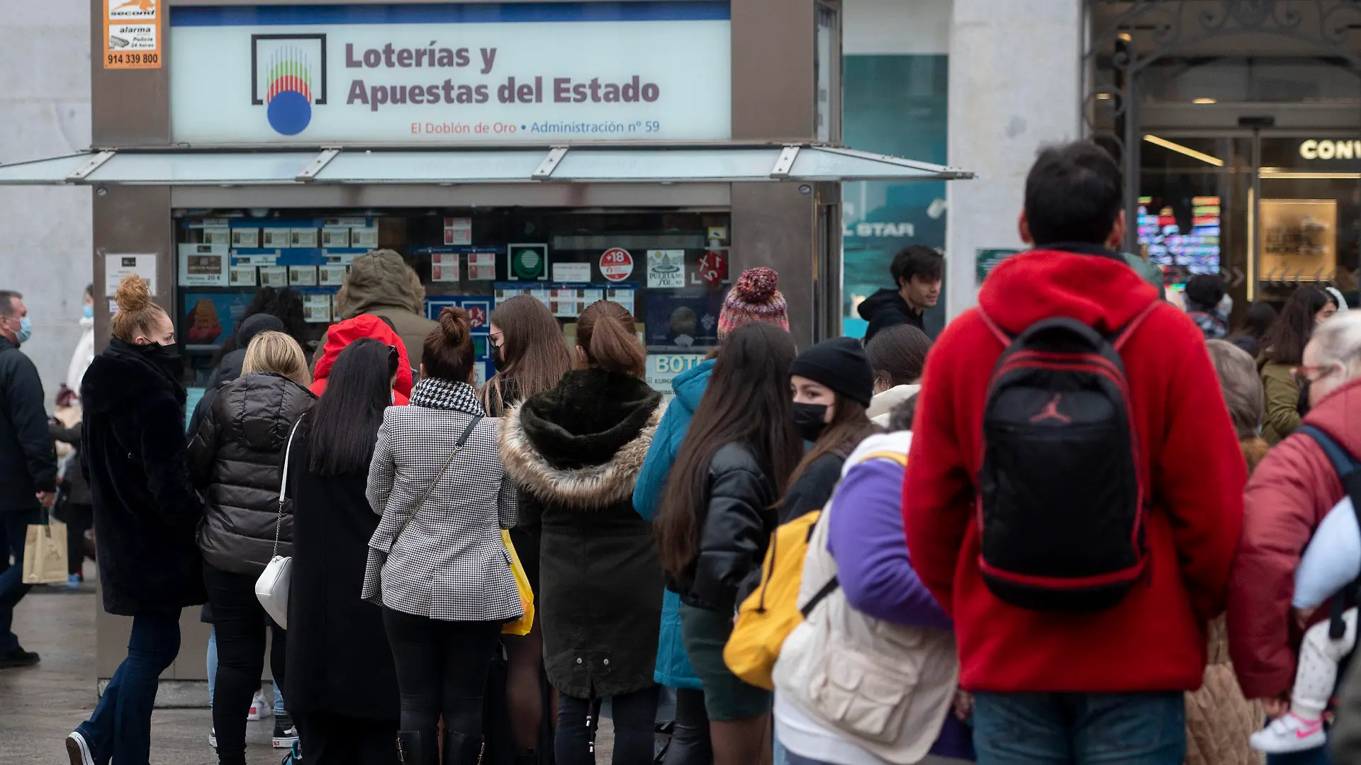ARCHIV - 07.12.2021, Spanien, Madrid: Weniger als drei Wochen vor der außerordentlichen Weihnachtslotterie-Ziehung von Spanien stehen mehrere Personen vor einer Lotto-Annahmestelle im Zentrum von Madrid Schlange. Jedes Jahr bilden sich vor der Weihnachtsziehung am 22. Dezember lange Schlangen vor der berühmten Lotto-Annahmestelle. Die Weihnachtslotterie gilt als größte und älteste Tombola der Welt. Die Gewinnzahlen der «Lotería de Navidad» werden von Schulkindern im Madrider Opernhaus vorgesungen und die Zeremonie live im TV übertragen. Foto: Alberto Ortega/EUROPA PRESS/dpa +++ dpa-Bildfunk +++