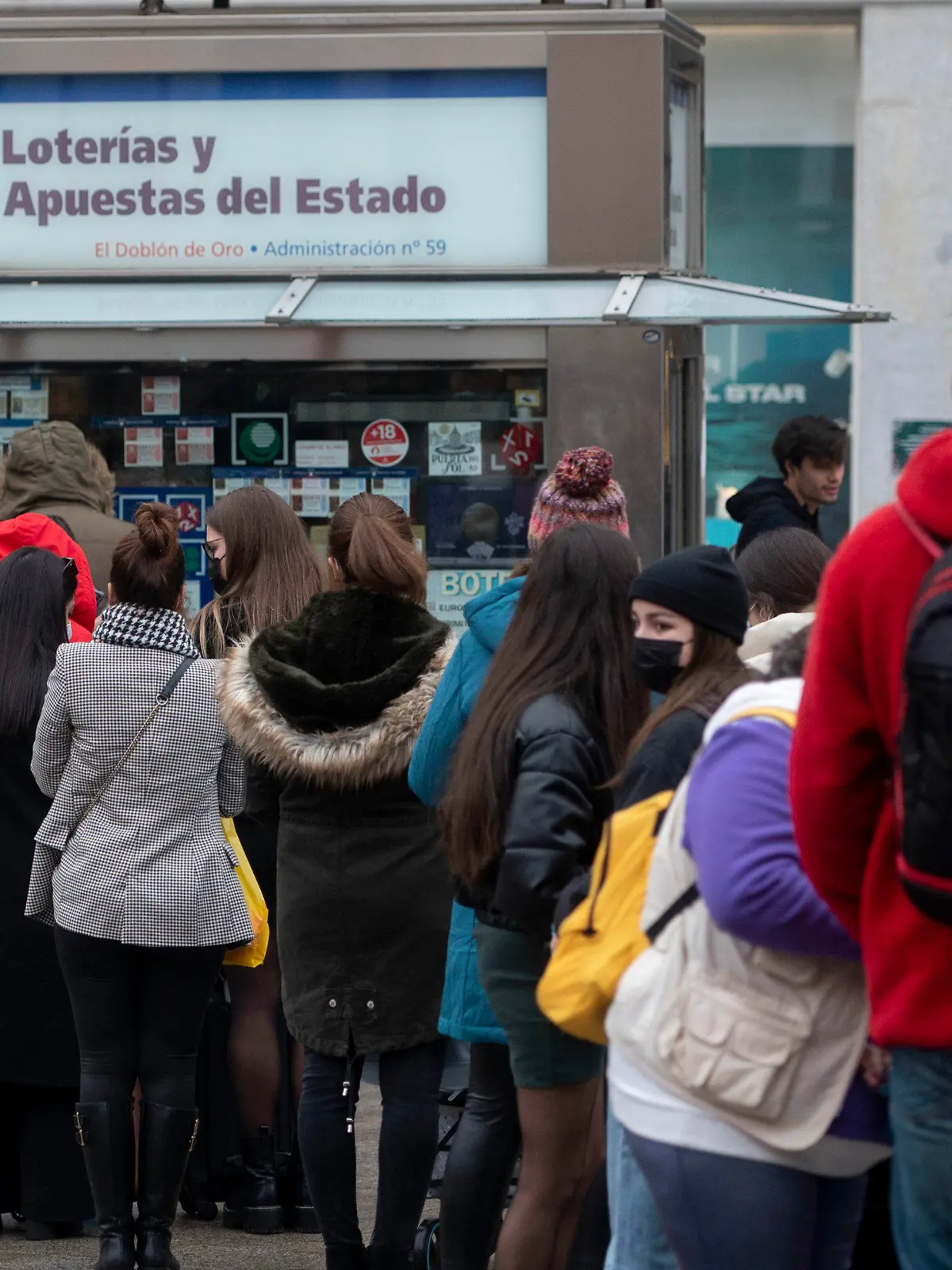 ARCHIV - 07.12.2021, Spanien, Madrid: Weniger als drei Wochen vor der außerordentlichen Weihnachtslotterie-Ziehung von Spanien stehen mehrere Personen vor einer Lotto-Annahmestelle im Zentrum von Madrid Schlange. Jedes Jahr bilden sich vor der Weihnachtsziehung am 22. Dezember lange Schlangen vor der berühmten Lotto-Annahmestelle. Die Weihnachtslotterie gilt als größte und älteste Tombola der Welt. Die Gewinnzahlen der «Lotería de Navidad» werden von Schulkindern im Madrider Opernhaus vorgesungen und die Zeremonie live im TV übertragen. Foto: Alberto Ortega/EUROPA PRESS/dpa +++ dpa-Bildfunk +++