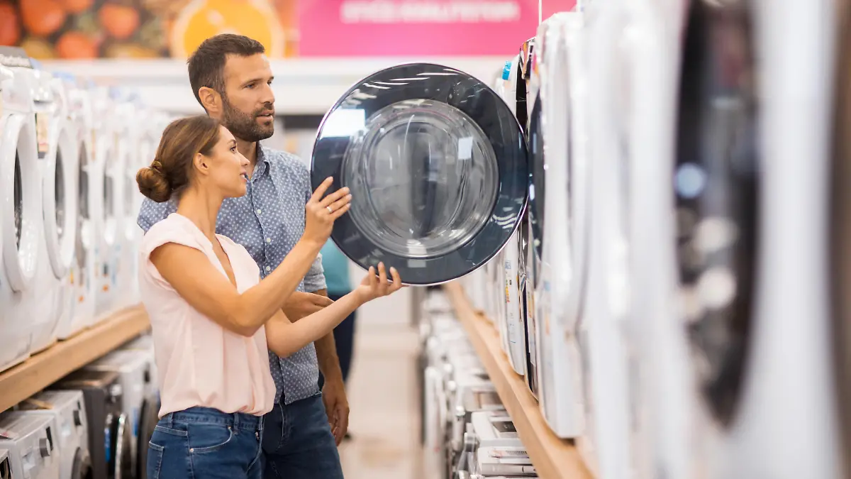 Young couple seen in a home appliances store in front of a drying machine.