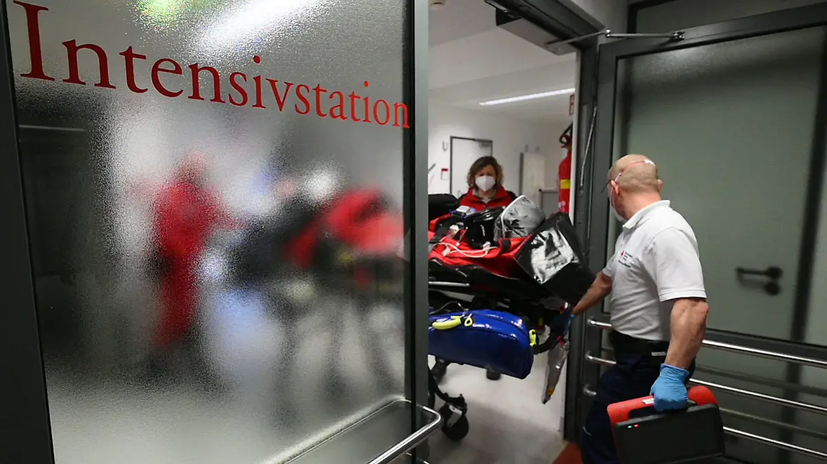 02.12.2021, Baden-Württemberg, Öhringen: Ein Rettungssanitäter hilft einem Team der DRF Luftrettung dabei, einen Patienten aus der Intensivstation des Hohenloher Krankenhauses zu schieben, um ihm zum DRF-Rettungshubschrauber Christoph 51 zu bringen. Die DRF transportierte bei dem Einsatz einen Patienten, der nicht an Covid-19 erkrankt ist, im DRF-Rettungshubschrauber Christoph 51 aus der Intensivstation des Hohenloher Krankenhauses auf die Intensivstation einer Reha-Klinik in Bayern. Nicht nur Covid-19-Patienten werden inzwischen per Hubschrauber von einer Klinik in eine andere transportiert. Um Kapazitäten auf den Intensivstationen zu schaffen, werden auch andere Patienten in andere Einrichtungen verlegt. Foto: Marijan Murat/dpa +++ dpa-Bildfunk +++