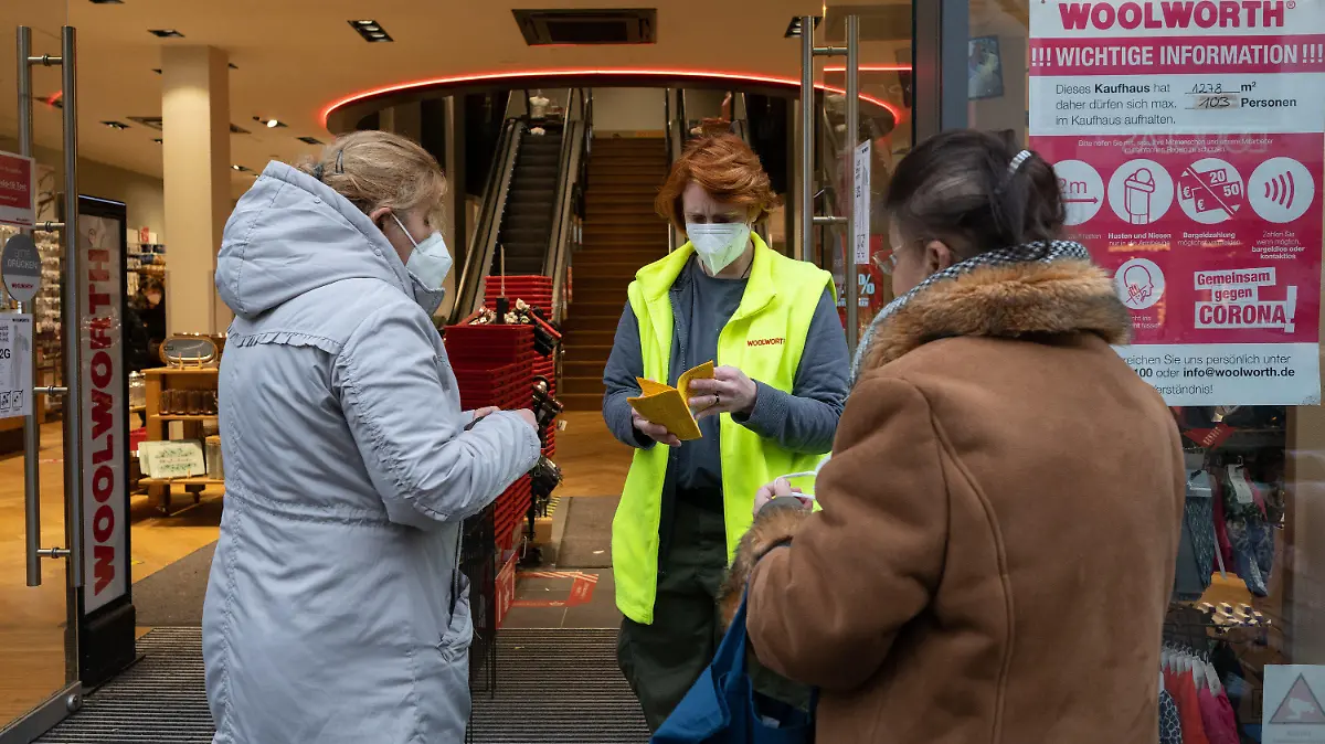 13.12.2021, Niedersachsen, Hildesheim: Kerstin Regner (M), stellv. Filialleiterin, kontrolliert am Eingang eines Kaufhauses von Woolworth Impfnachweise von Kunden. In Niedersachsen müssen sich laut der jetzt geltenden neuen Corona-Verordnung die Menschen auf verschärfte Schutzmaßnahmen einstellen. Im Einzelhandel gilt jetzt größtenteils die 2G-Regel: Zugang nur für Geimpfte und Genesene. Foto: Julian Stratenschulte/dpa +++ dpa-Bildfunk +++