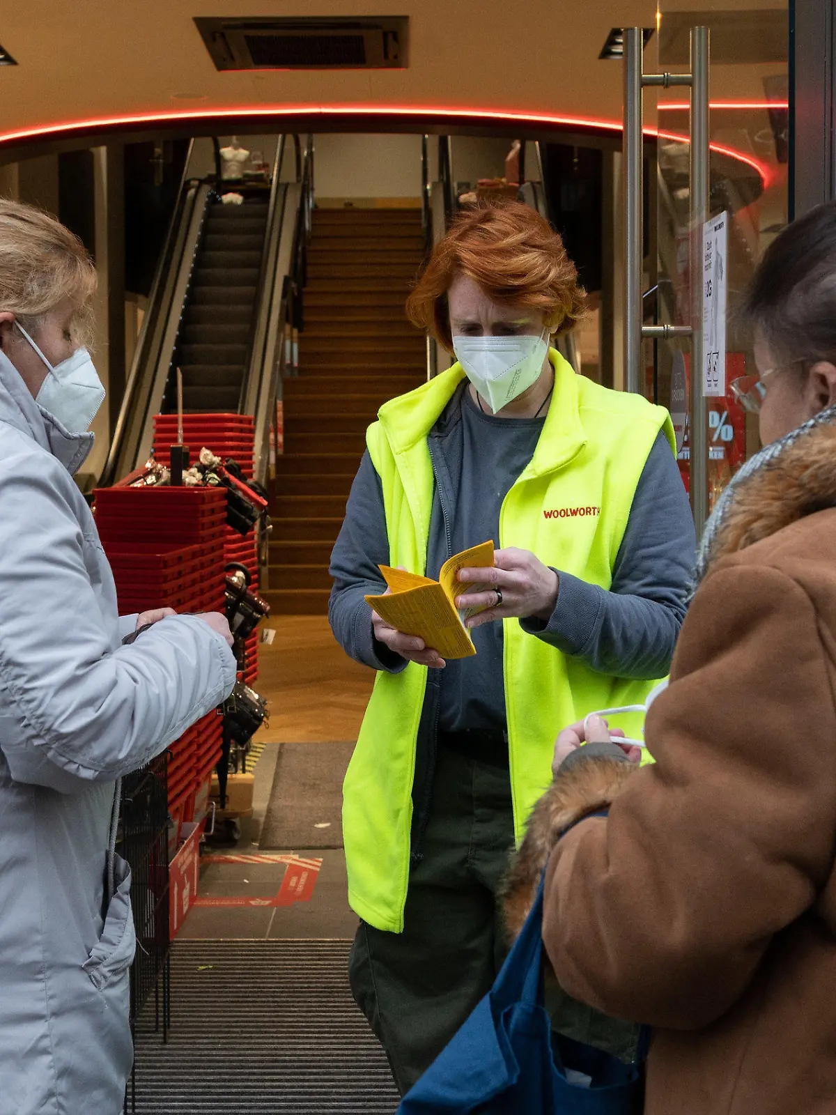 13.12.2021, Niedersachsen, Hildesheim: Kerstin Regner (M), stellv. Filialleiterin, kontrolliert am Eingang eines Kaufhauses von Woolworth Impfnachweise von Kunden. In Niedersachsen müssen sich laut der jetzt geltenden neuen Corona-Verordnung die Menschen auf verschärfte Schutzmaßnahmen einstellen. Im Einzelhandel gilt jetzt größtenteils die 2G-Regel: Zugang nur für Geimpfte und Genesene. Foto: Julian Stratenschulte/dpa +++ dpa-Bildfunk +++