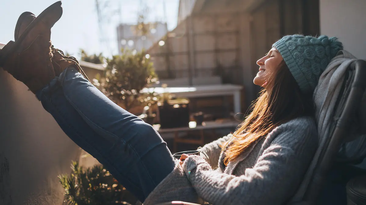 Photo of a young woman taking a few minutes off to relax on the balcony over the city, on a beautiful, sunny, autumn day