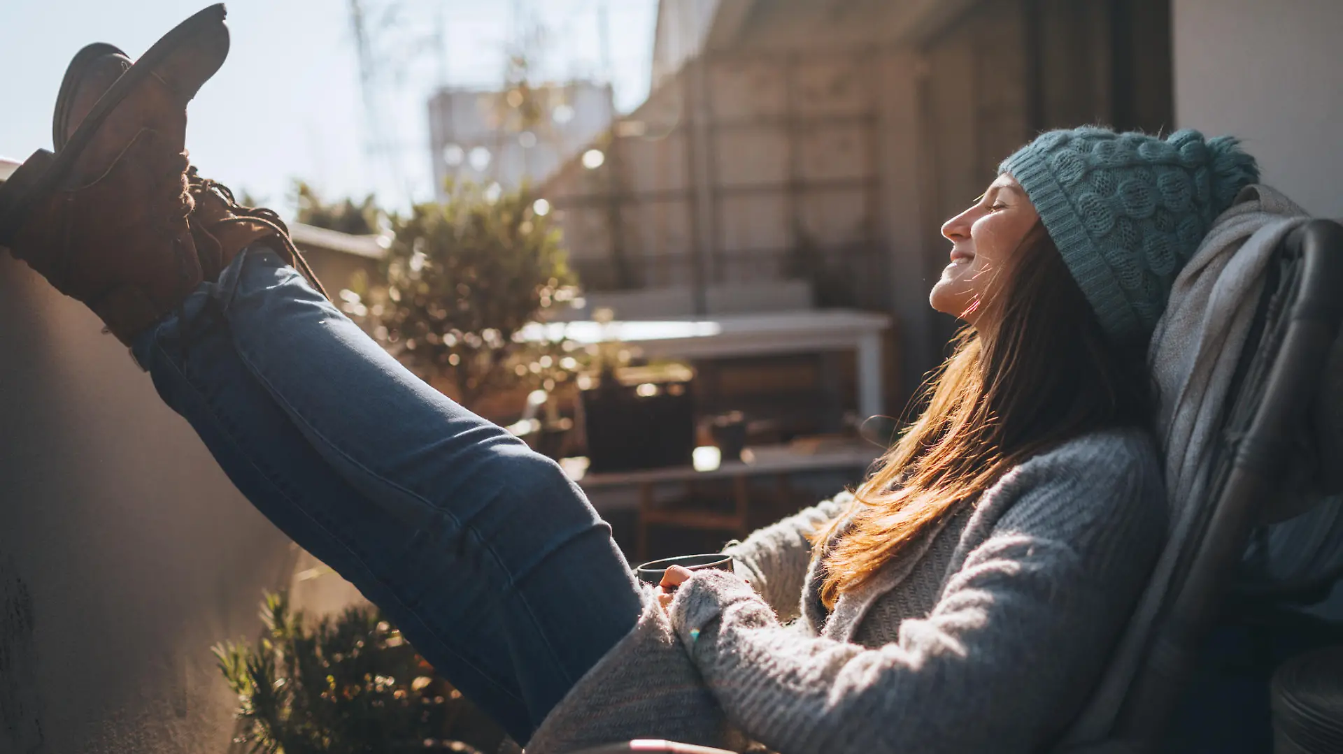 Photo of a young woman taking a few minutes off to relax on the balcony over the city, on a beautiful, sunny, autumn day