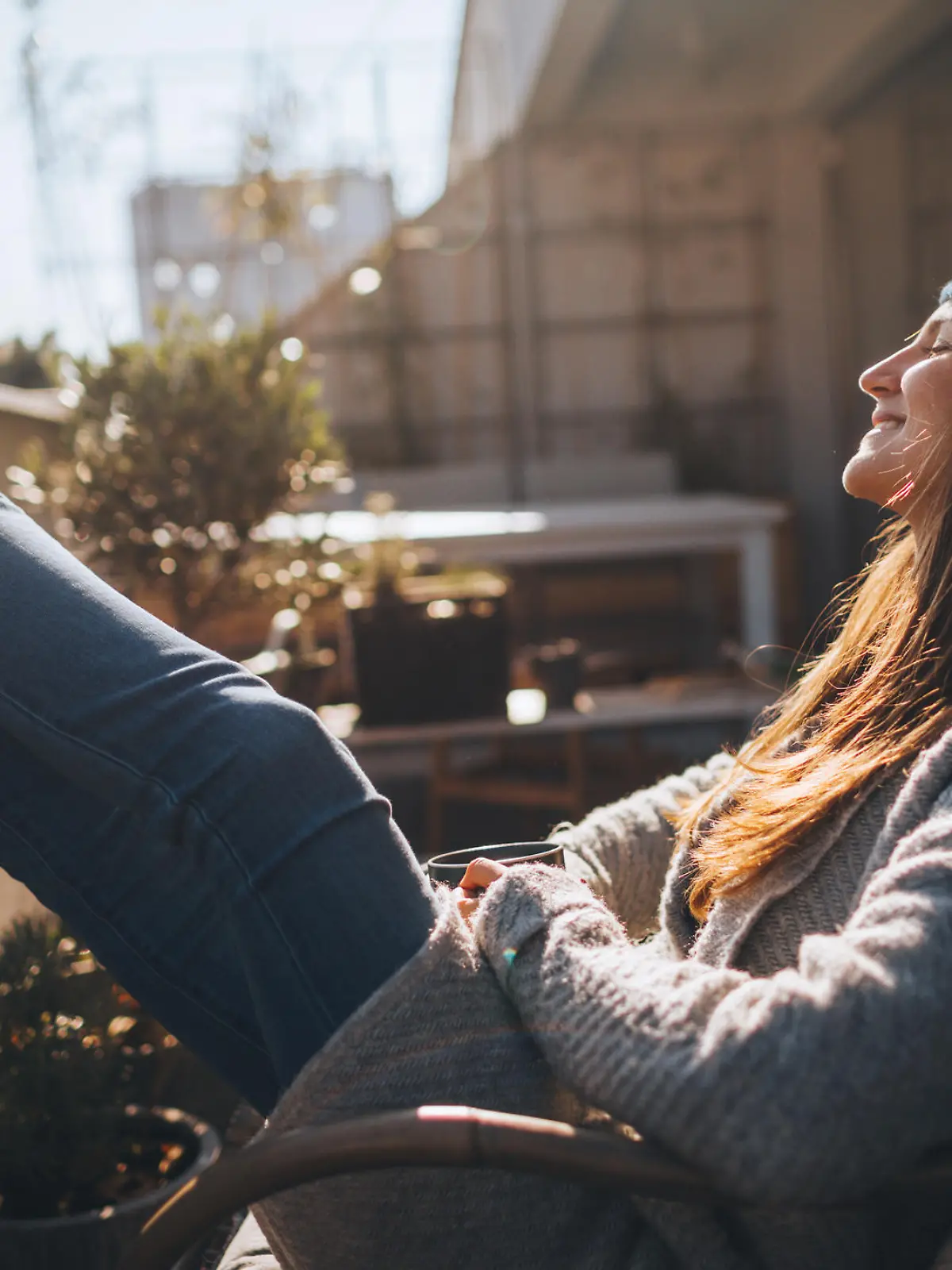Photo of a young woman taking a few minutes off to relax on the balcony over the city, on a beautiful, sunny, autumn day