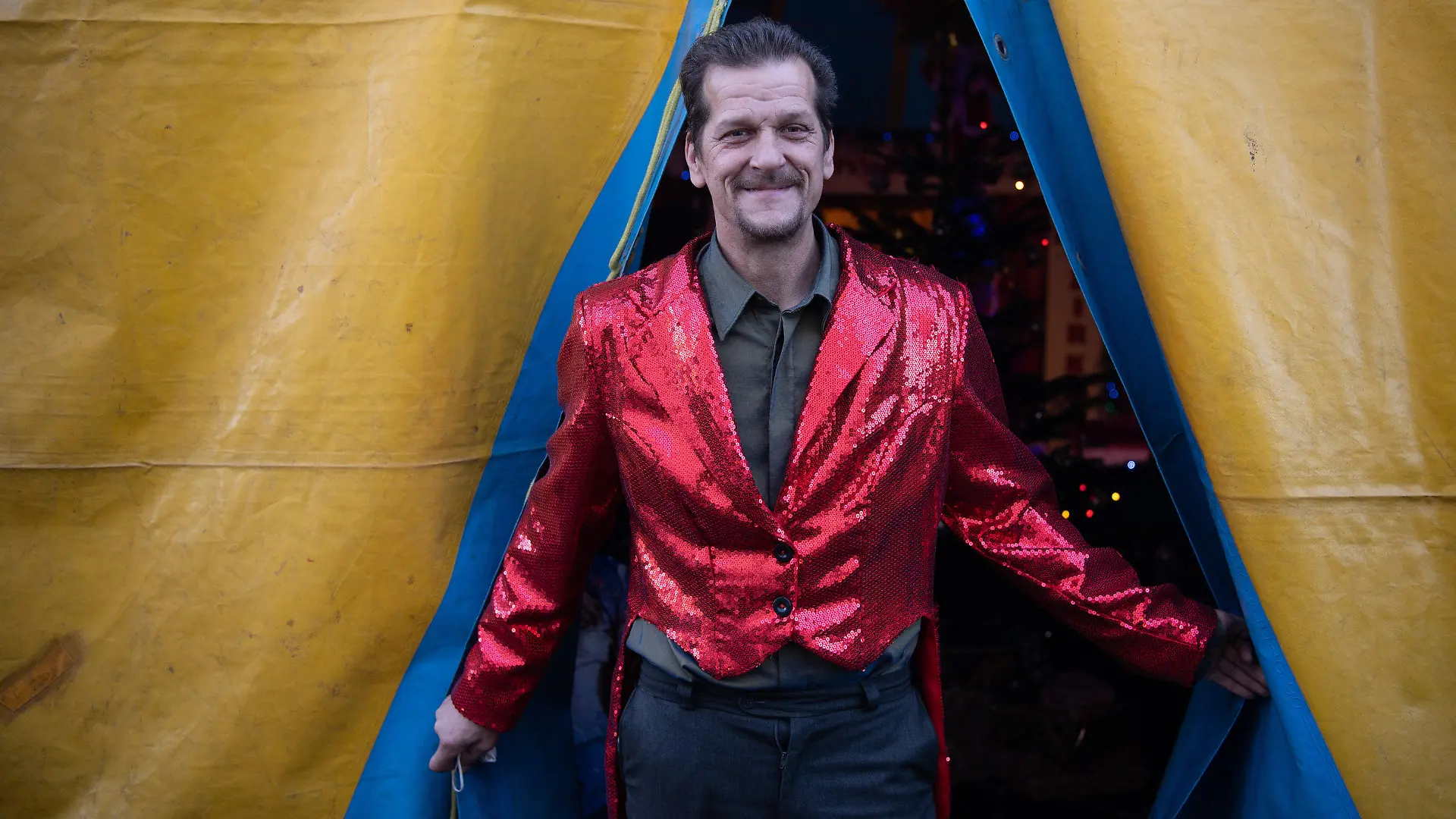 20.12.2021, Hessen, Frankfurt/Main: Zirkusdirektor Tino Krämer wartet im ·Familienzirkus Delmonde· auf den Beginn der Vorstellung. Nachdem der Zirkus aufgrund der Corona-Pandemie in den vergangen zwei Jahren kaum Vorstellungen anbieten konnte, kann die Betreiberfamilie auch im zweiten Corona-Winter kaum die laufenden Kosten decken. Aufzugeben ist für die aus zwölf Mitgliedern bestehende Zirkustruppe dennoch keine Option. Foto: Boris Roessler/dpa +++ dpa-Bildfunk +++